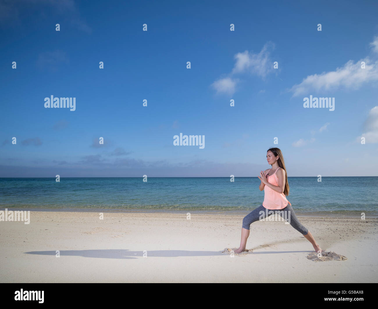 Junge Frau praktizieren Yoga am Strand von Motobu, Okinawa, Japan Stockfoto