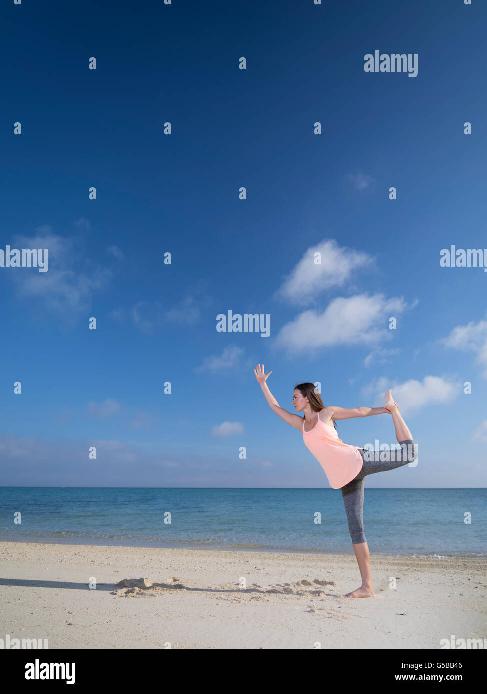 Junge Frau praktizieren Yoga am Strand von Motobu, Okinawa, Japan Stockfoto