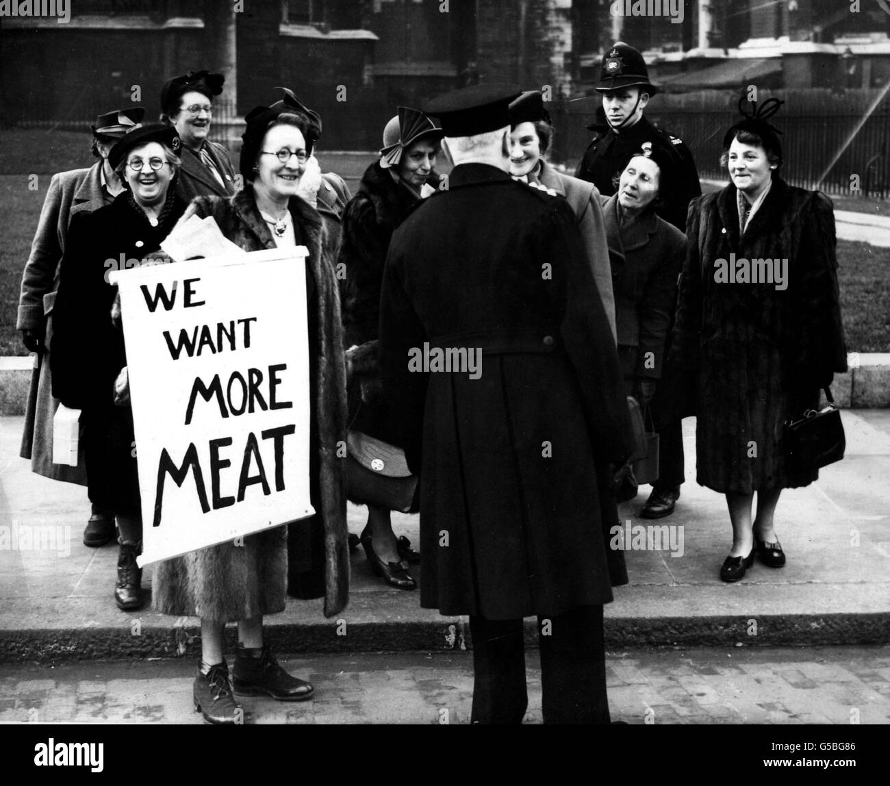 FLEISCHRATIONIERUNG 1951: Die Mitglieder der British Housewives' League riefen „Wir wollen mehr Fleisch!“ und entweiteten sich vor dem Eingang des britischen Unterhauses St. Stephen, London. Hier sprechen die Mitglieder der Liga mit einem Plakat mit einem Polizisten. Stockfoto