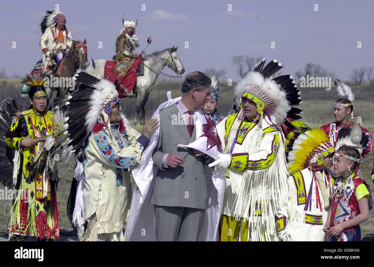 Der Prinz von Wales trägt eine weiße Satindecke mit burgunderroten Sternen, die ihm als seltenes Geschenk einheimischer indischer Ältester über die Schultern gelegt wurde, um Freundschaft und Schutz zu signalisieren, im Wanuskewin Heritage Park, einem Zentrum der Ureinwohner in der Provinz Saskatchewan in Kanada, Die er am vierten Tag seiner sechstägigen Tour durch Kanada besuchte. Prinz Charles erhielt auch einen indischen Namen - von einem einheimischen Häuptling, der es sich beim Entspannen in einer Sauna erdachte und nun den Indianern als Kisikawpisim Kamiyowahpahmikroot bekannt sein soll, was grob übersetzt bedeutet: 'Die Sonne wacht auf eine gute Weise.' Stockfoto