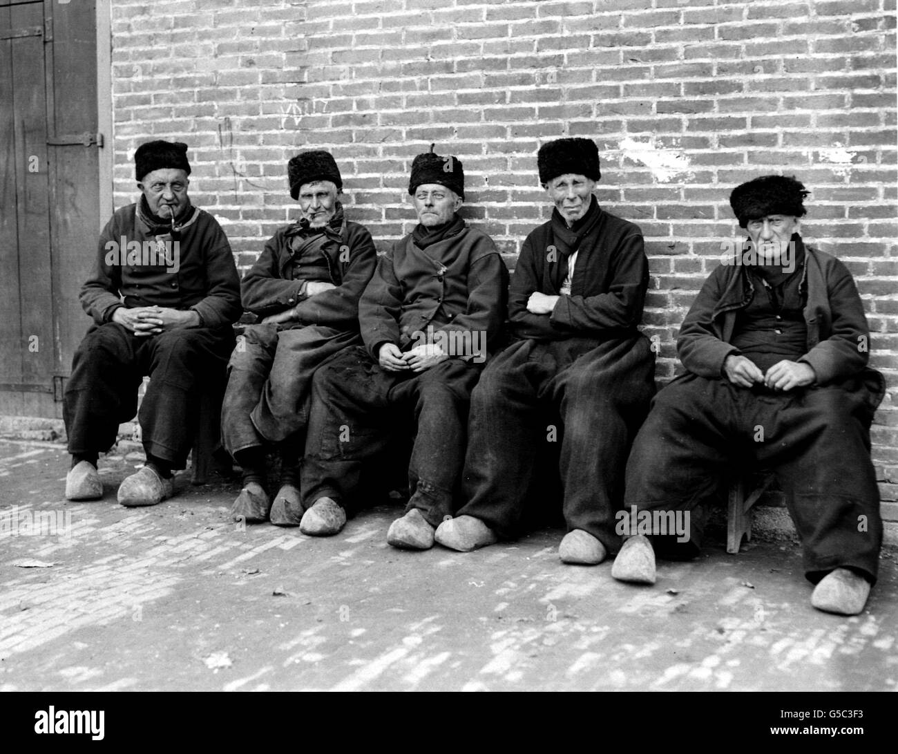 HOLLAND 1910: Eine Gruppe älterer Holländer in traditioneller Tracht in Marken, Niederlande. Die Männer tragen alle Clogs und Pelzmützen. Stockfoto