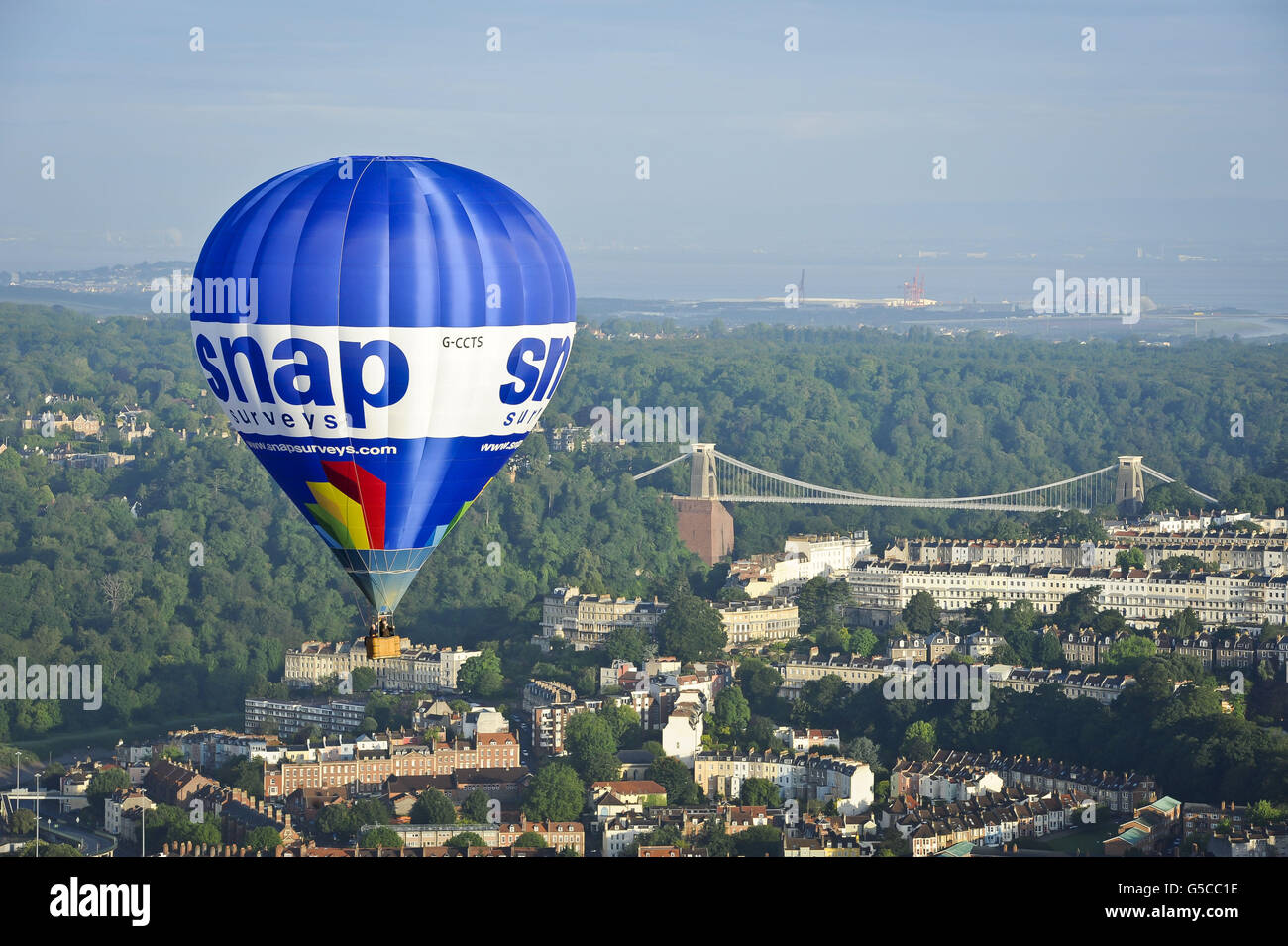 Ein Heißluftballon fliegt an der Clifton Suspension Bridge von Brunel in Bristol vorbei, in der die 34. Internationale Ballonfest von Bristol im Ashton Court Estate stattfinden wird, während sich Ballonfahrer aus der ganzen Welt zu dem größten Ballonevent in Europa versammeln. Stockfoto