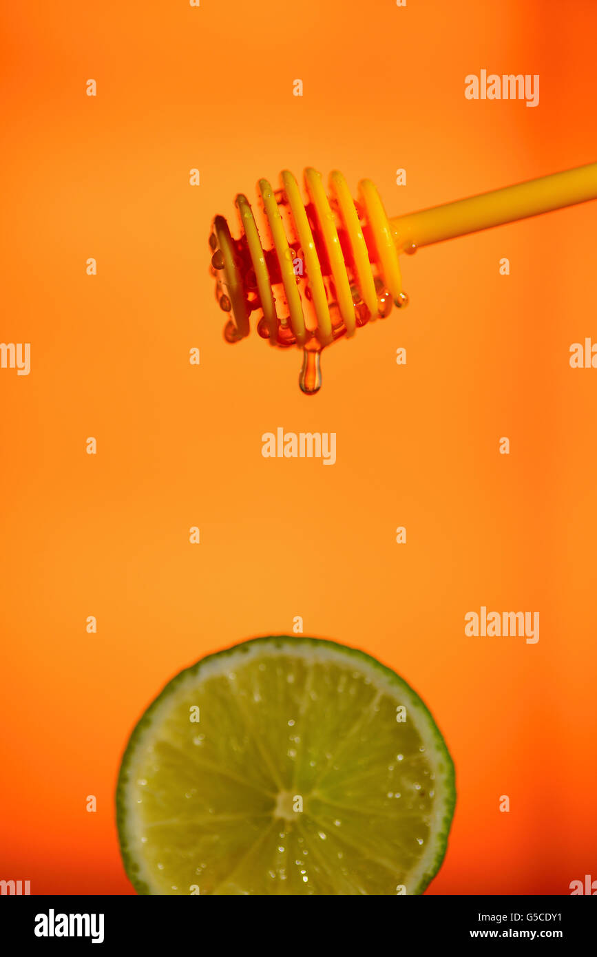 Honig fließt auf Zitrone auf gelbem Hintergrund Stockfoto