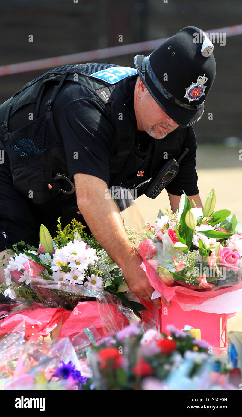 Ein Polizist stellt Blumen neben andere Blumengebete am Make-Shift-Denkmal für Tia Sharp in New Addington, Croydon, in der Nähe des Hauses der Großmutter Christine Sharp, die 12 Jahre alt ist, wo gestern eine Leiche gefunden wurde. Stockfoto