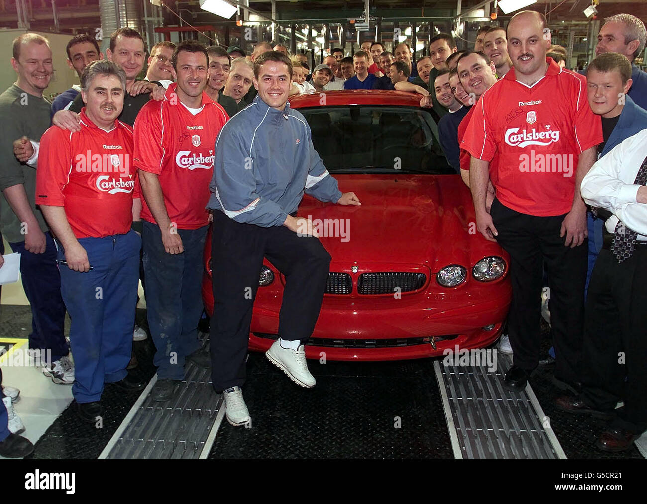 Liverpool und England Fußballspieler Michael Owen sitzt auf einem neuen Jaguar X-Type, genannt "Baby Jag", mit Arbeitern im Jaguar Werk in Halewood auf Merseyside. Der Luxus-Automobilhersteller hat für sein neues Modell Voraufträge im Wert von rund 100 Millionen entgegengenommen. * ...der am 23 2001. Mai in den Handel kommt, ist der X-TYPE der erste Einstieg von Jaguar in den Luxus-Executive-Pkw-Markt. Stockfoto