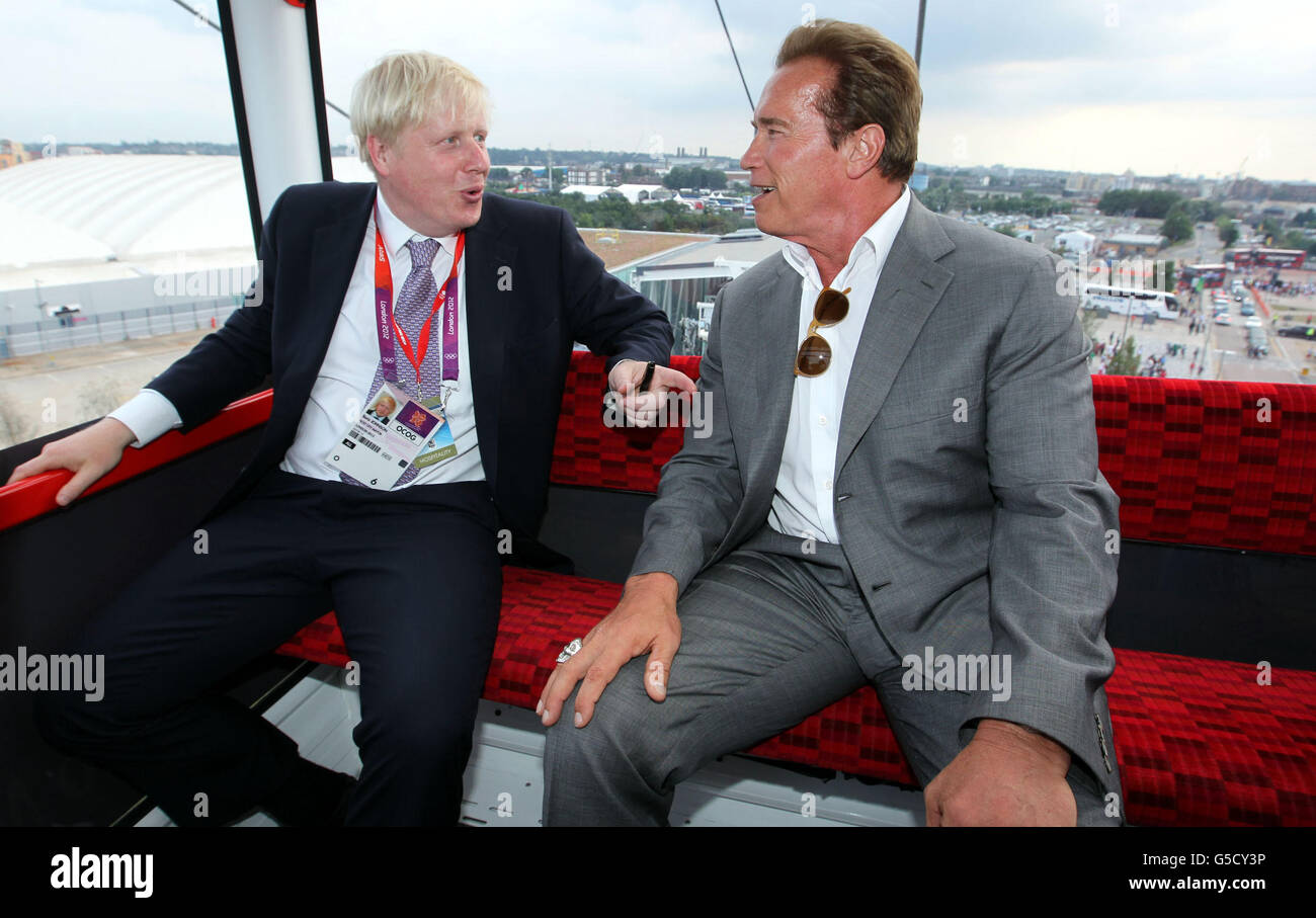 Bürgermeister Boris Johnson (links) und Arnold Schwarzenegger fahren mit der Emirates-Seilbahn von Greenwich zum Excel in den Docklands, nachdem sie den olympischen Basketball in Greenwich beobachtet haben. Stockfoto