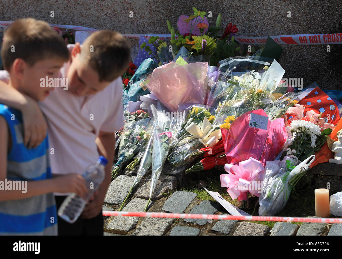 Zwei einheimische Jungen trösten sich gegenseitig, nachdem sie Blumen an der Make-Shift-Gedenkstätte für Tia Sharp in New Addington, Croydon, in der Nähe des Heims der Großmutter Christine Sharp der vermissten 12-Jährigen gelegt hatten, wo gestern ein Leichnam gefunden wurde. Stockfoto