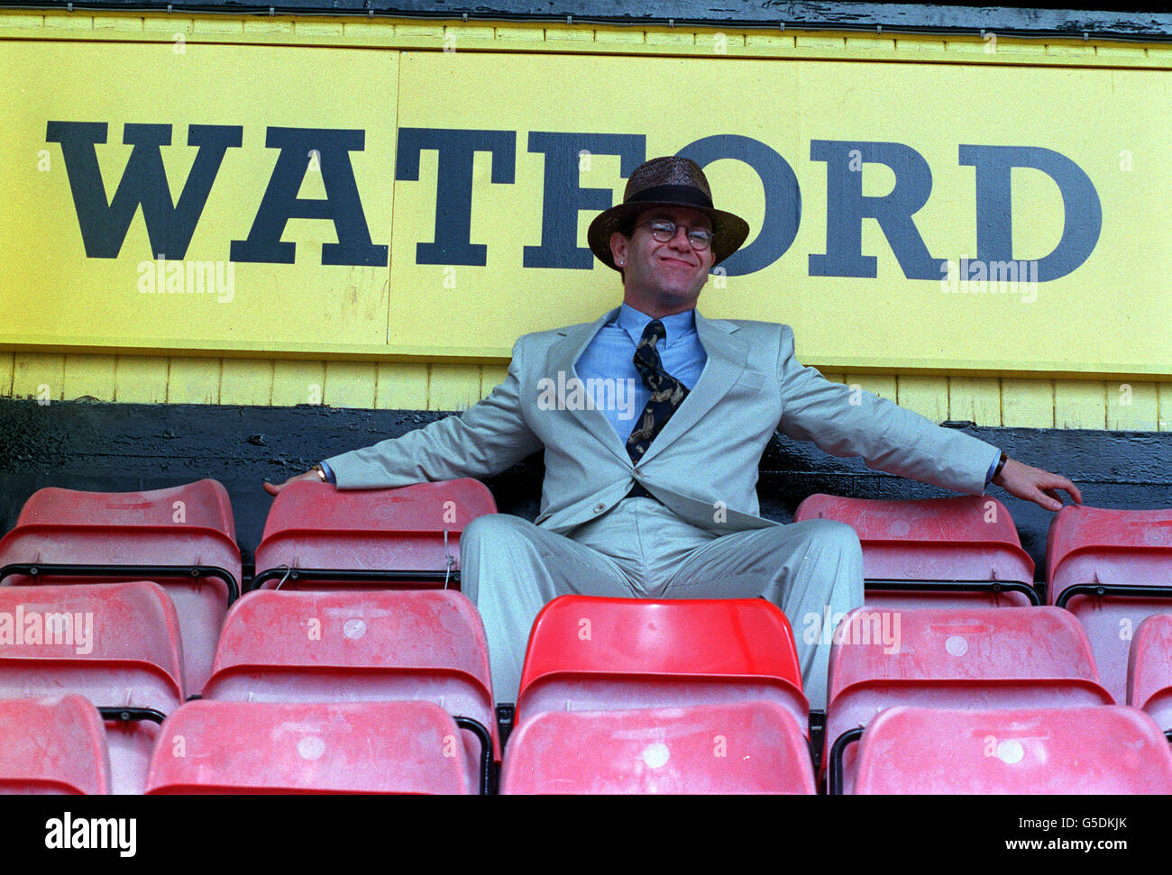 1991: Sänger Elton John sitzt auf den Terrassen auf dem Vicarage Road Ground des Watford FC, wo er bekannt gab, dass er Direktor des Clubs geworden sei. Stockfoto