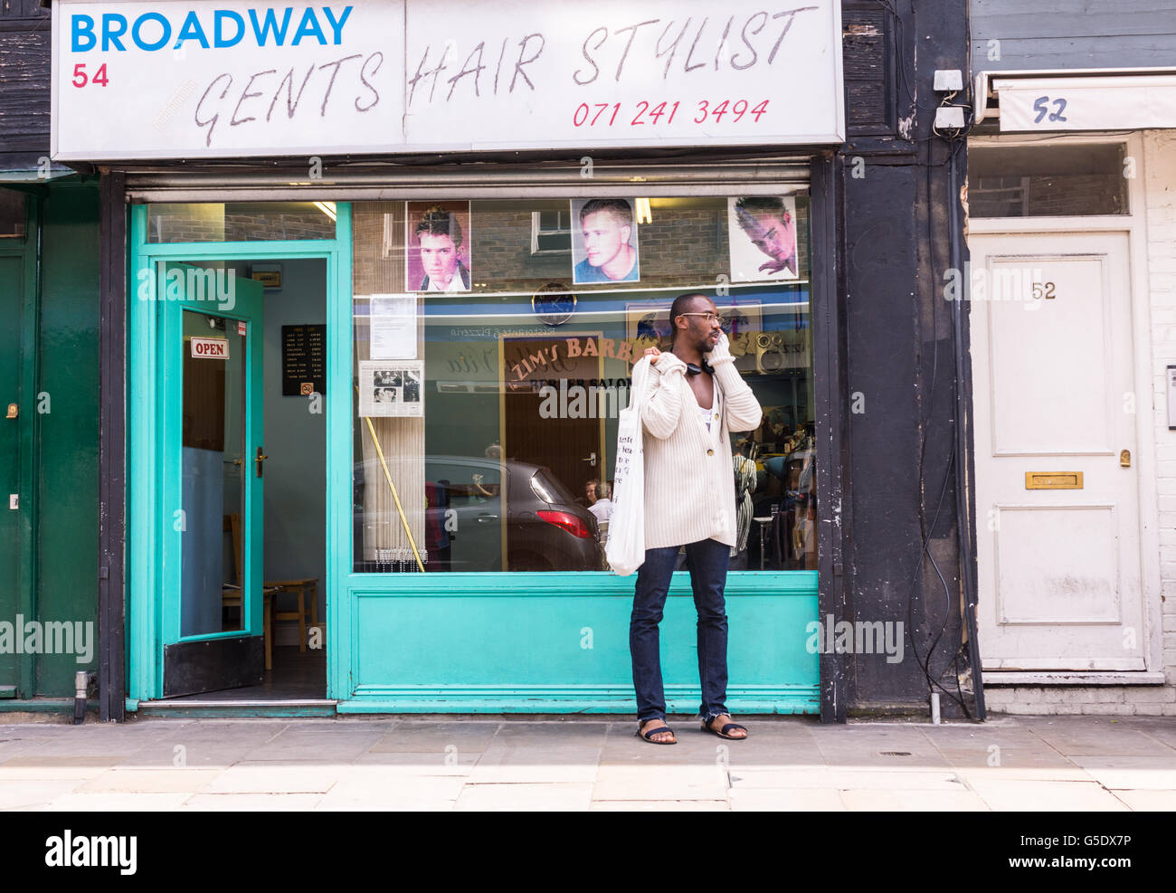Hipster afro Mann am Telefon außerhalb eines Herren Friseur im Cool hipster Bereich broadway Markt, East London Stockfoto
