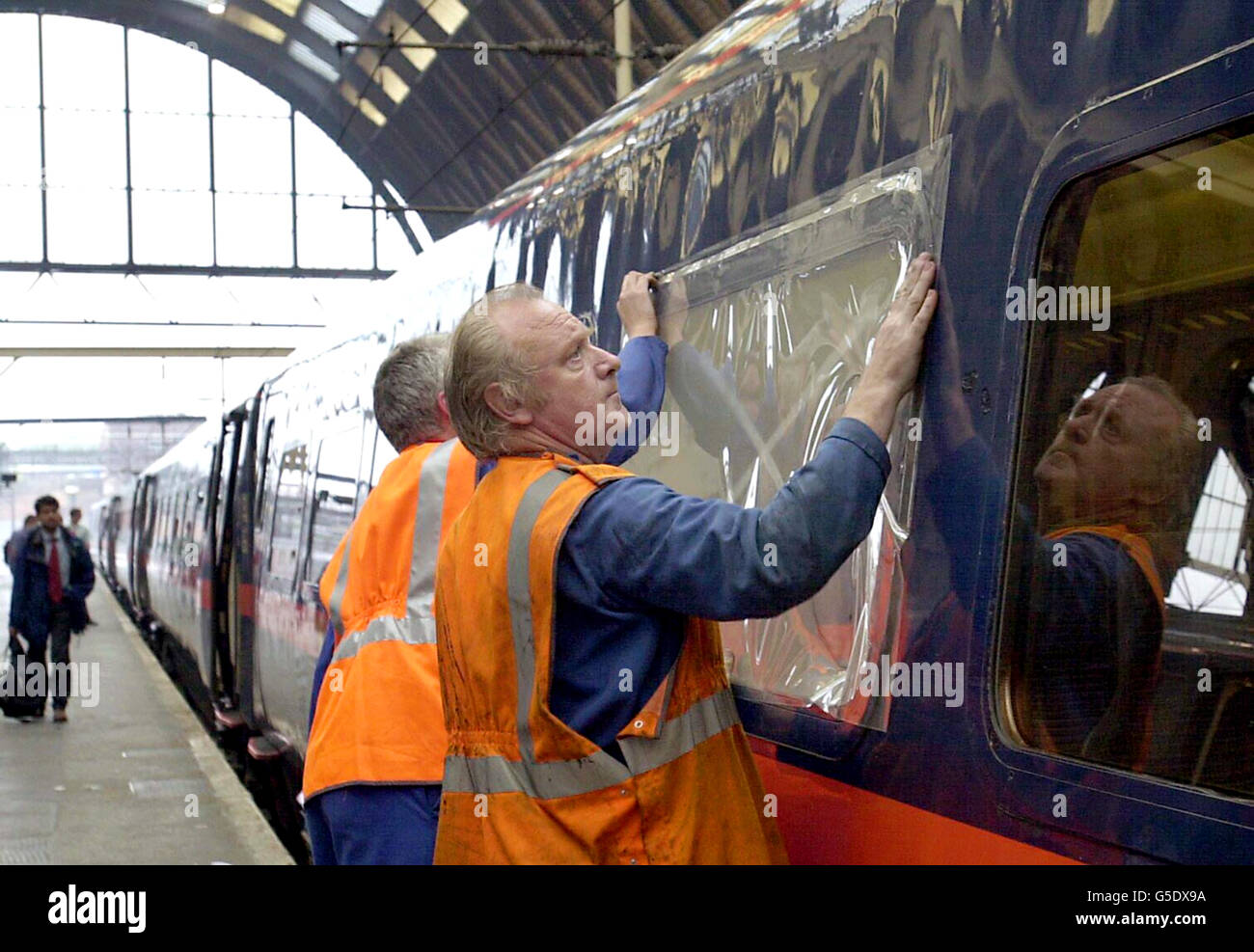 Auf einem GNER-Zug, der 15.05 von Leeds nach Kings Cross, am Bahnhof Kings Cross in London, ist eine temporäre Plastikfolie über den Fenstern aufgeklebt. Das äußere Glas in fünf Fenstern wurde von Steinen und Ziegelsteinen zerschlagen, die von Vandalen im Wakefield-Gebiet auf den Zug geworfen wurden. Stockfoto