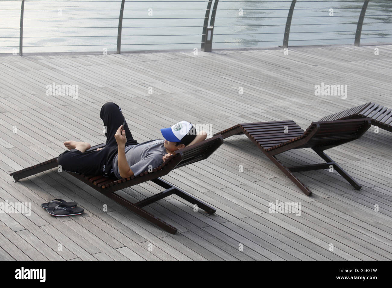 Ein Mann, relaxen und entspannen in einem Strandkorb an der Promenade von Marina Bay in Singapur Stockfoto