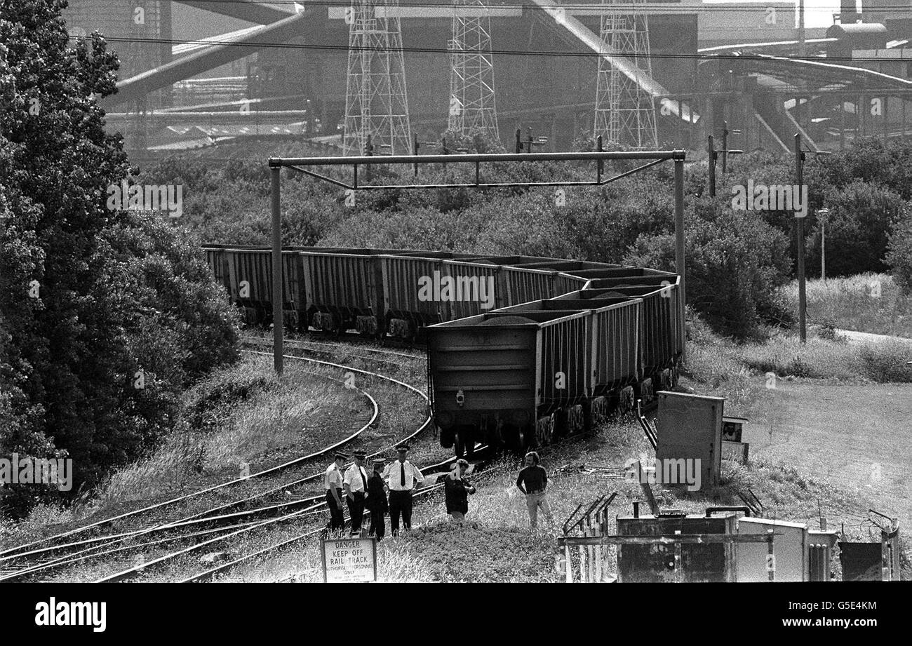 Zwei Vertreter des Bergarbeiterstreikens am Gleis mit Polizisten, als ein mit Eisenerz beladener Zug in das Stahlwerk Llanwen in Südwales einfährt. Stockfoto