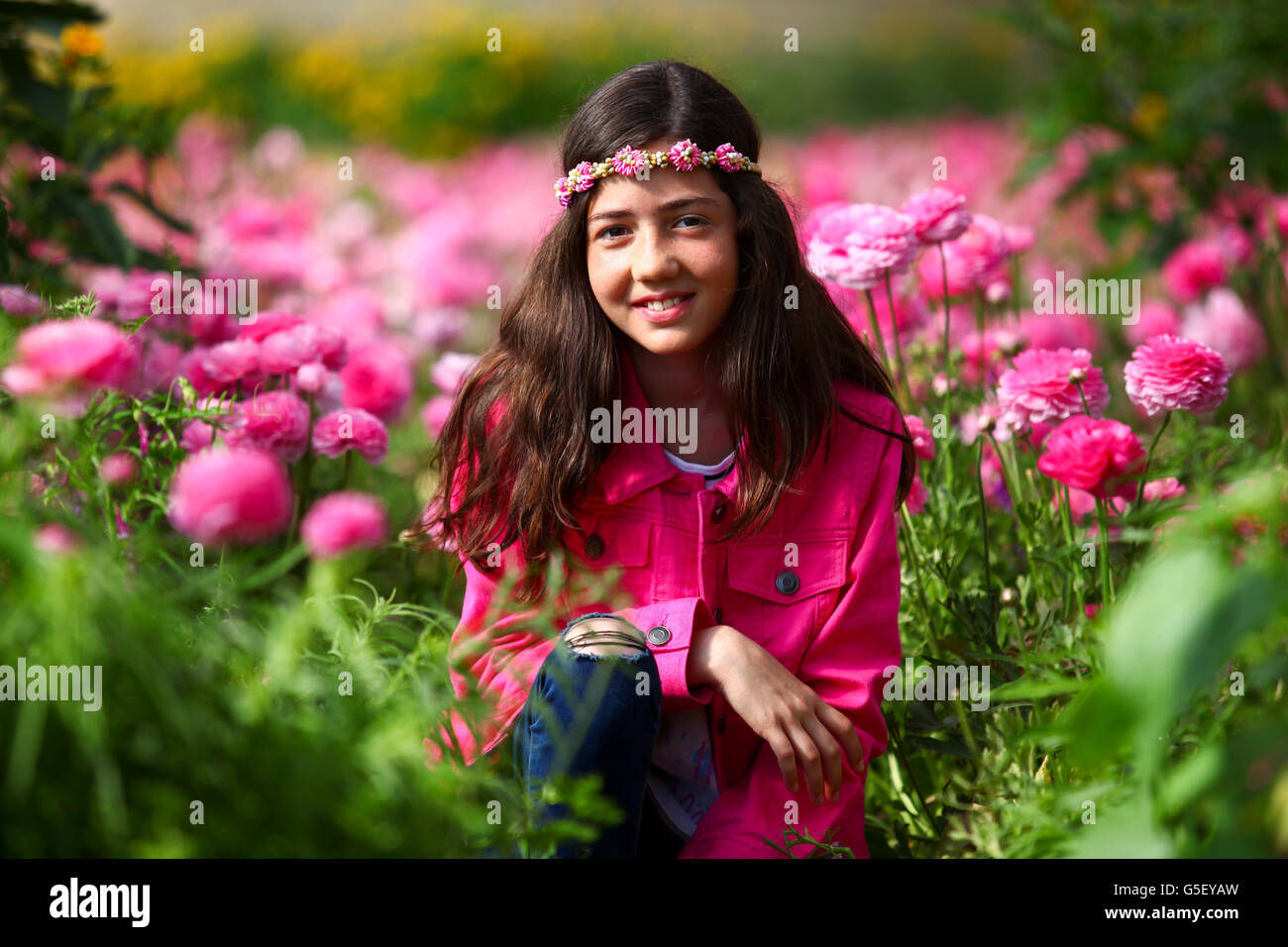 Preteen Mädchen 12 in einem Gewächshaus aus rosa Blüten Stockfoto
