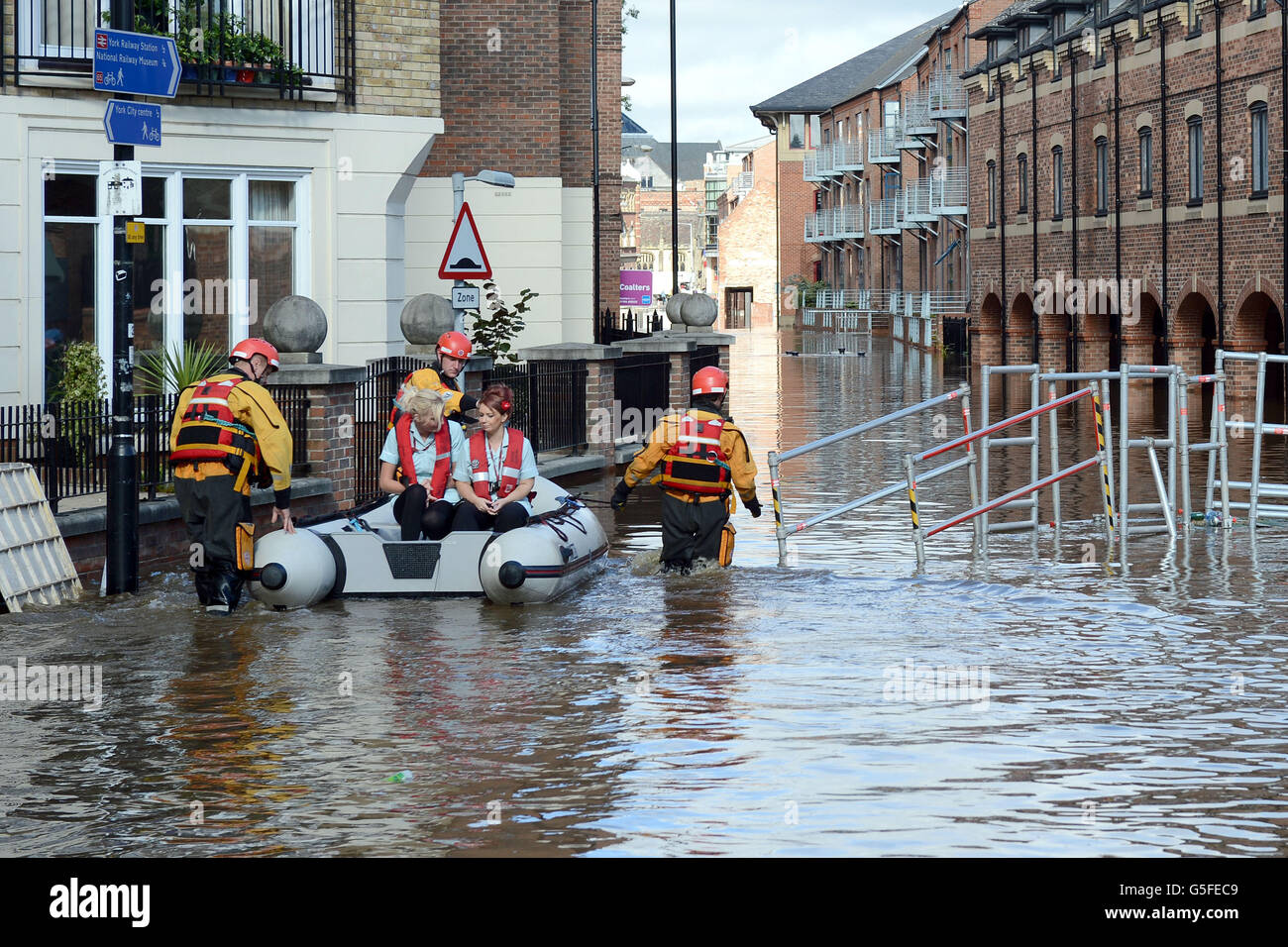 Feuerwehrmannschaften aus York bringen Pflegepersonal mit dem Boot in ein Wohnheim in Skeldergate, da viele Straßen im Stadtzentrum von York weiterhin mit Flutwasser bedeckt sind. Stockfoto