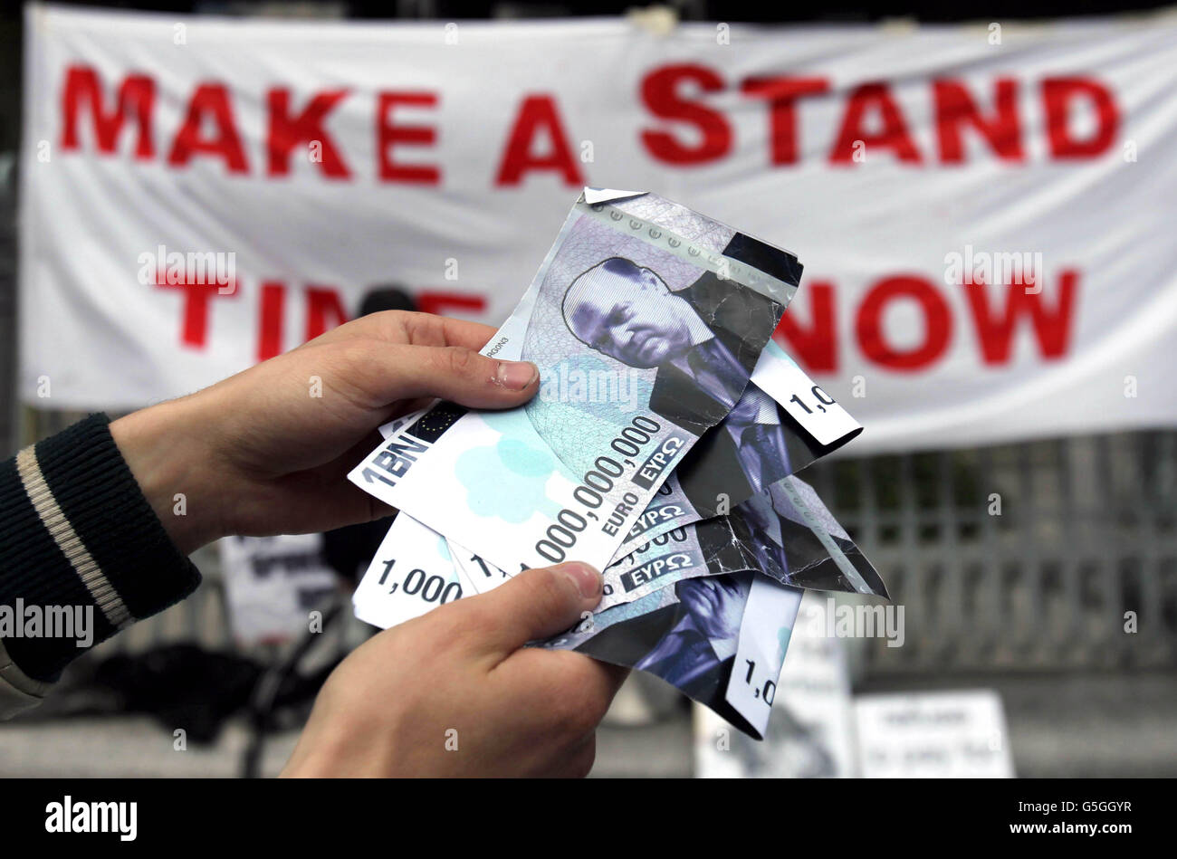 Ein Protestor übergibt gefälschte Banknoten mit Finanzminister Michael Noonan während einer Demonstration vor der Zentralbank in Dublin, um ein Jahr seit Beginn des Lagers Occupy Dame Street zu markieren. Stockfoto