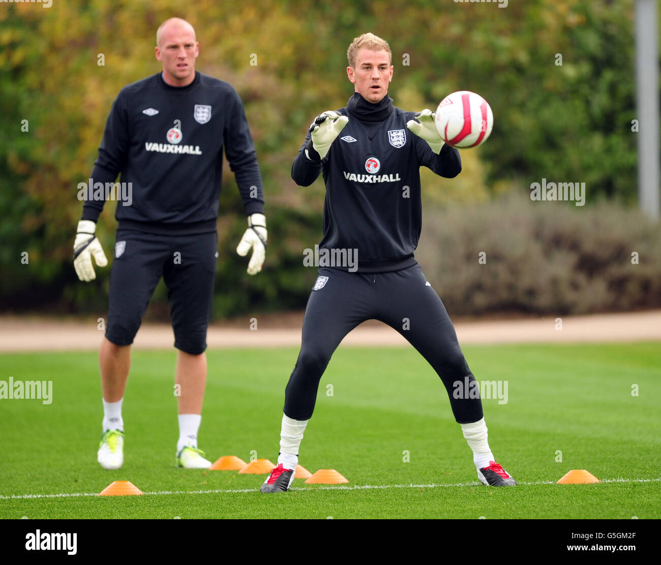 Fußball - FIFA Fußball-Weltmeisterschaft 2014 - Qualifikation - Gruppe H - England gegen San Marino - England Training Session - London Colney. Der englische Joe Hart beim Training, beobachtet von John Ruddy Stockfoto
