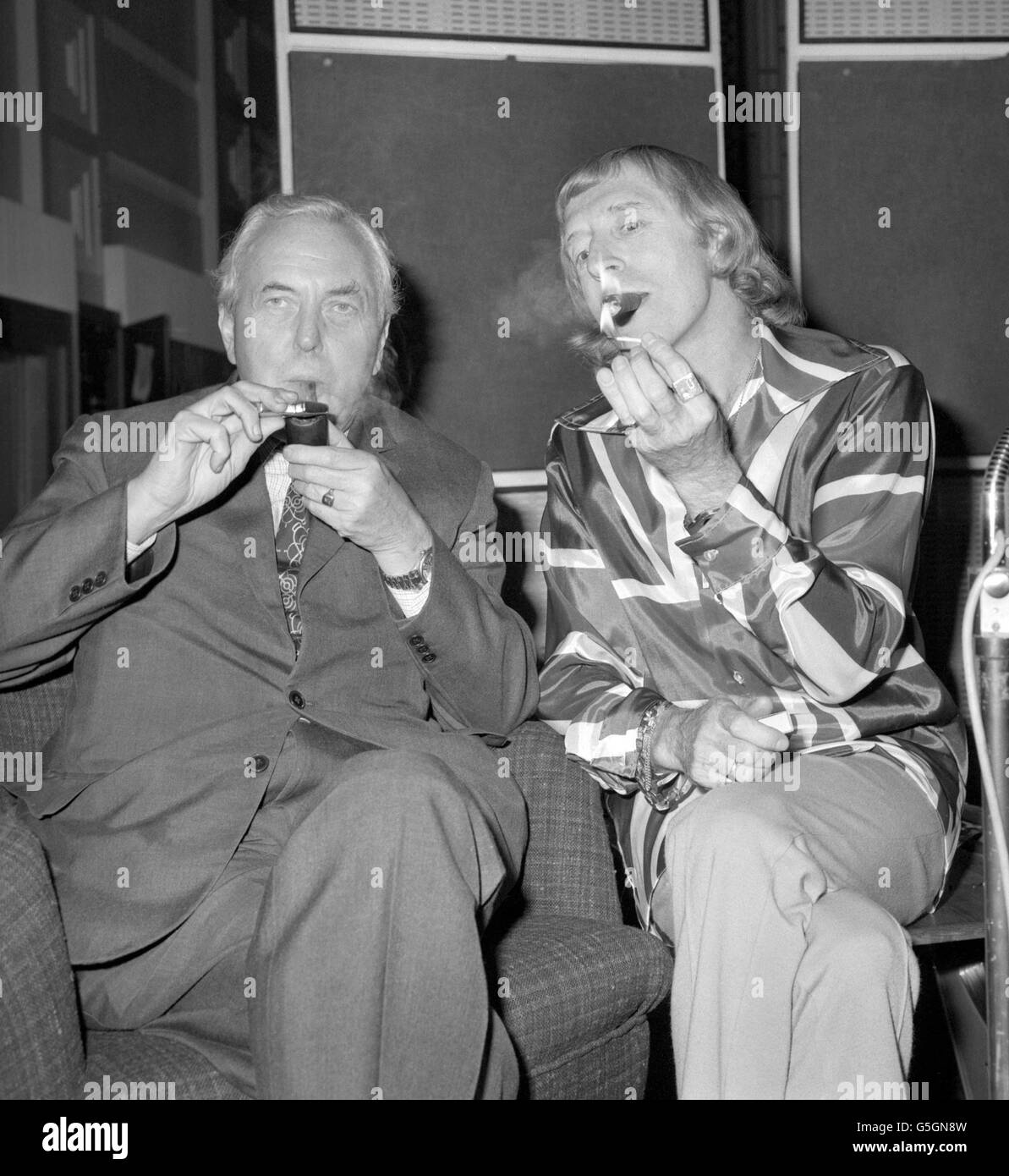TV- und Radiomoderstar Jimmy Savile genießt eine Zigarre mit Mitrauchter und Sir Harold Wilson während ihres Treffens im Broadcasting House in London. Herr Savile interviewte den ehemaligen Premierminister bei einer Aufnahmesitzung für sein Radio-1-Programm Speakeasy. Stockfoto