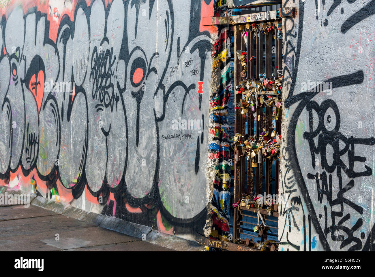 Abschnitte der Berliner Mauer, nun bedeckt mit Straßenkunst und Lovelocks in der East Side Gallery in Berlin, Deutschland Stockfoto