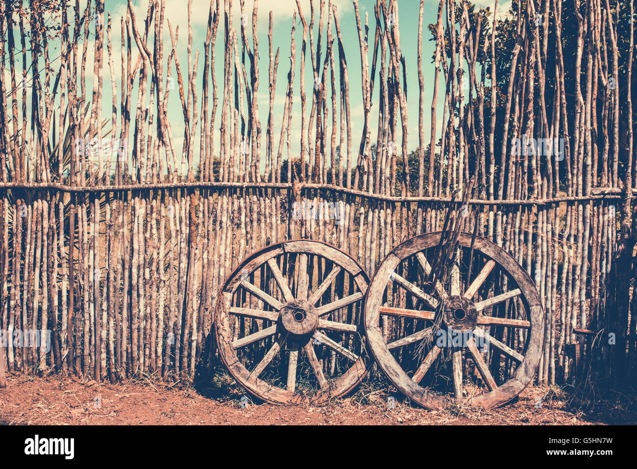 Zwei alte Wagenräder in der Nähe der Holzzaun. Alte Karre Rad als Symbol und Vorstellung von Glück und Schicksal. Altmodischen Sepia Farben Stockfoto