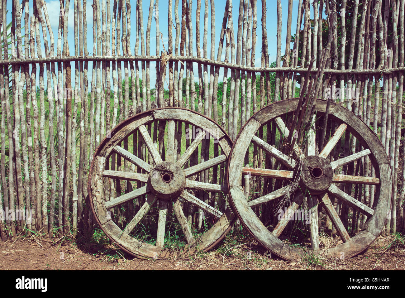 Zwei alte Wagenräder in der Nähe der Holzzaun. Alte Karre Rad als Symbol und Vorstellung von Glück und Schicksal. Altmodischen Sepia Farben Stockfoto