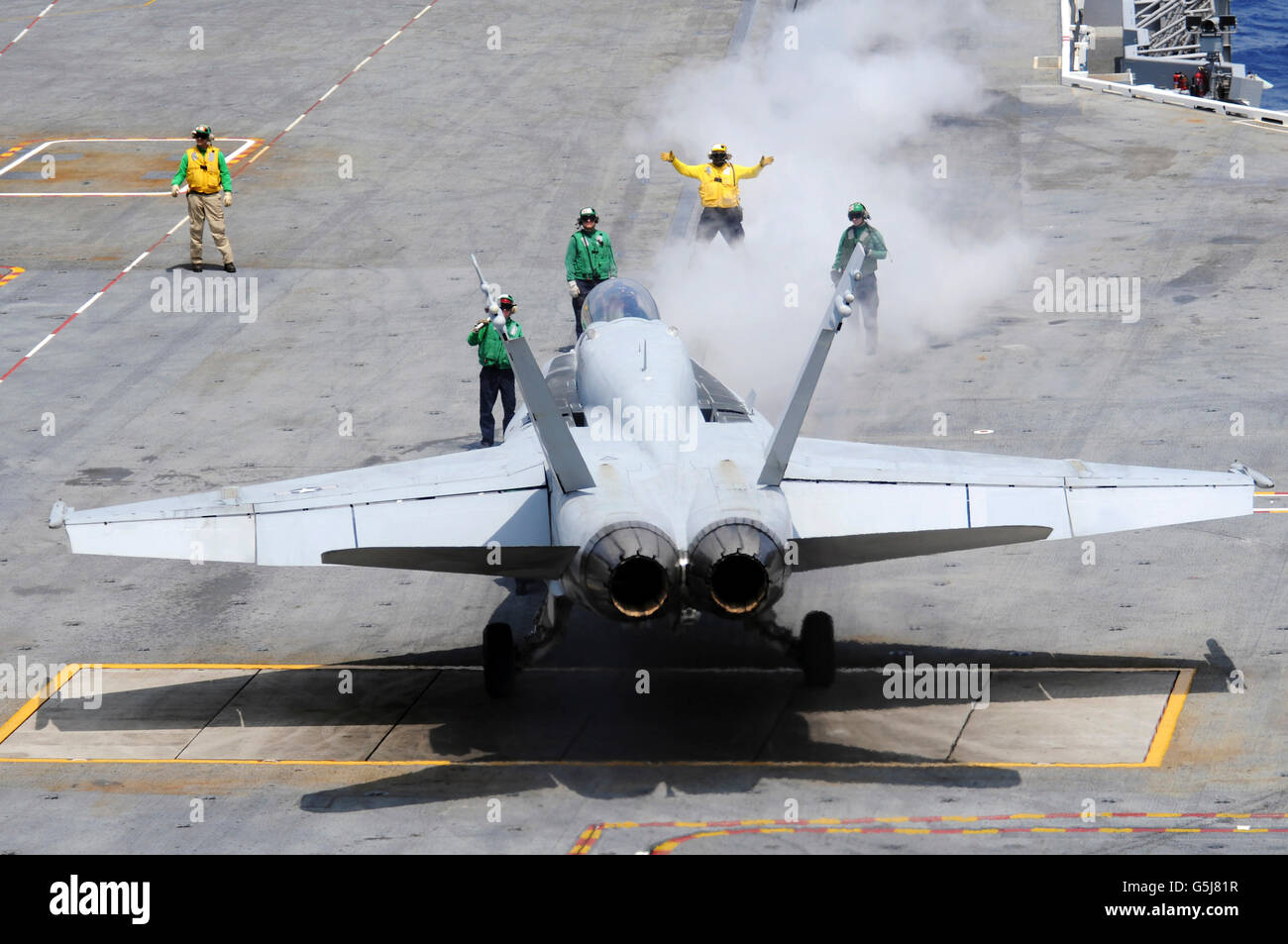 Ein Flugzeug-Direktor führt eine F/A-18 Hornet auf das Katapult an Bord des Flugzeugträgers USS Carl Vinson. Stockfoto