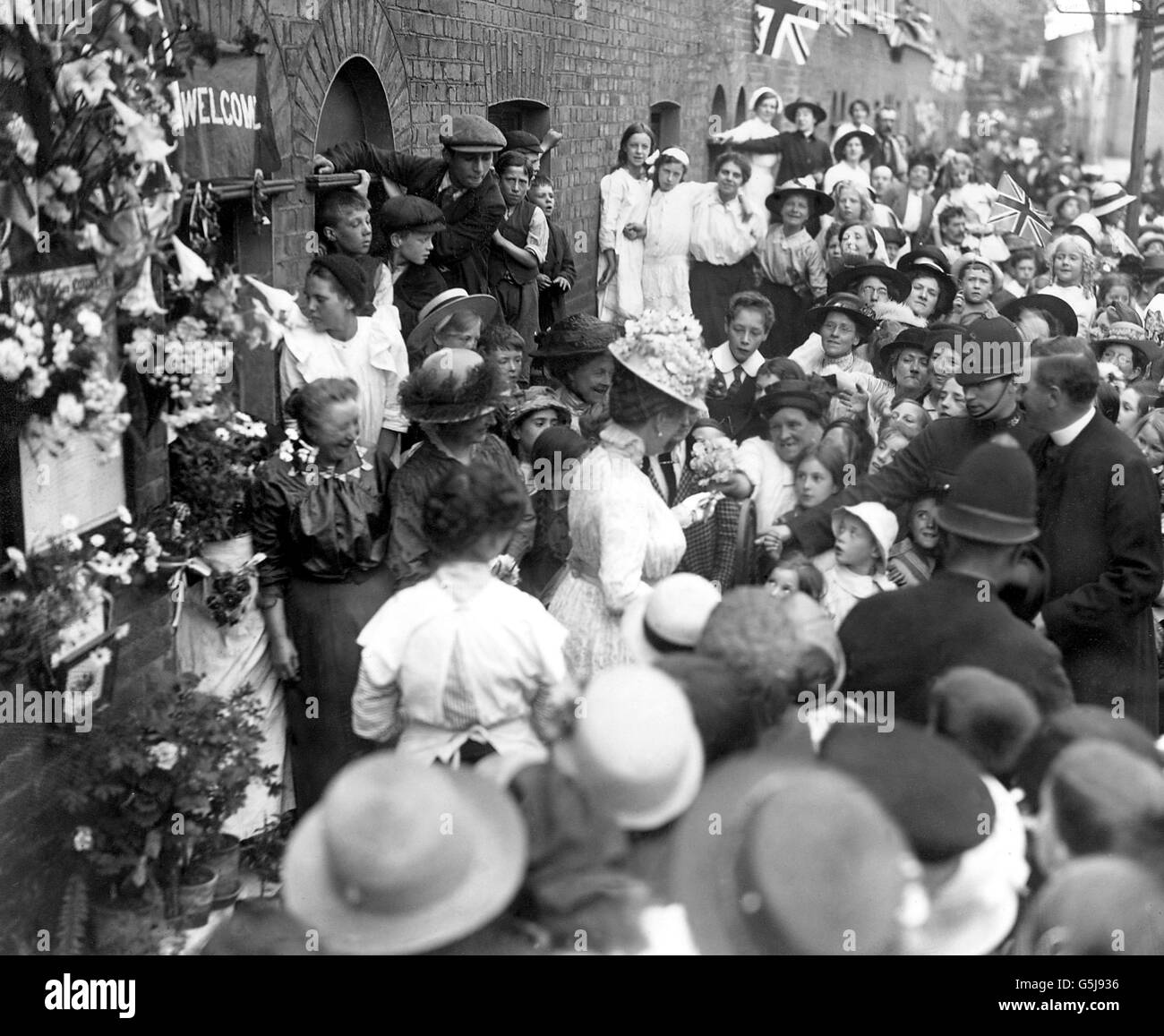 Queen Mary verteilt einige ihrer Blumen an Kinder, nachdem sie eine Ehrenrolle auf der Palace Road in Hackney betrachtet hat. Stockfoto