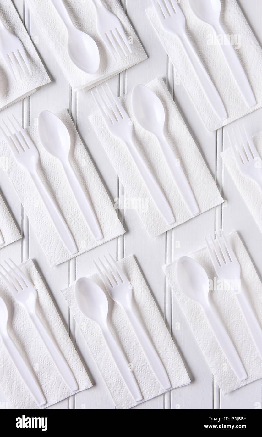 Draufsicht der weiße Servietten mit weißen Kunststoff Gedecke auf einem weißen Tisch. Hochformat. Stockfoto