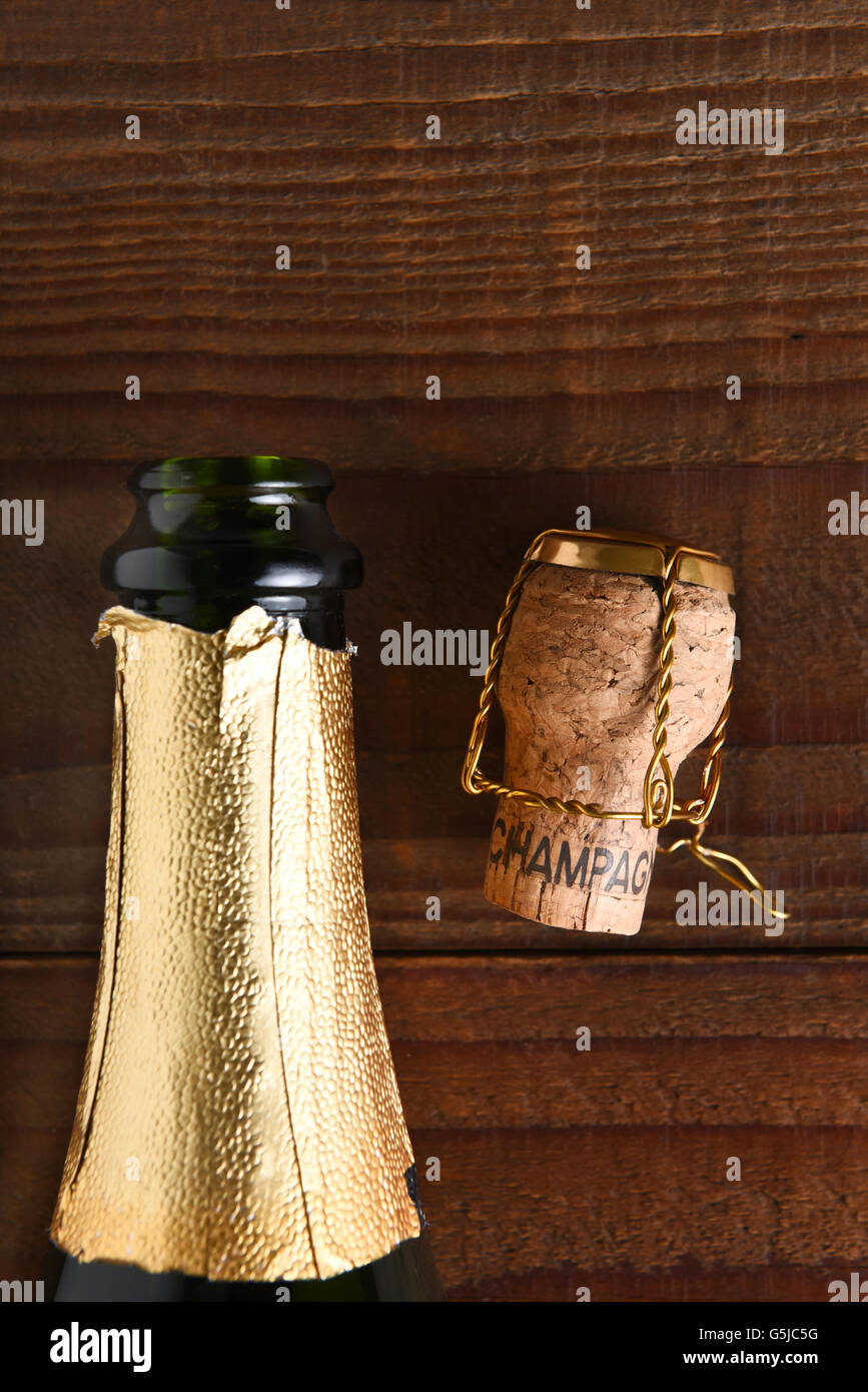 Draufsicht auf eine geöffnete Flasche Champagner neben dem Kork und Käfig. Hochformat auf dunklem Holz mit Textfreiraum. Stockfoto