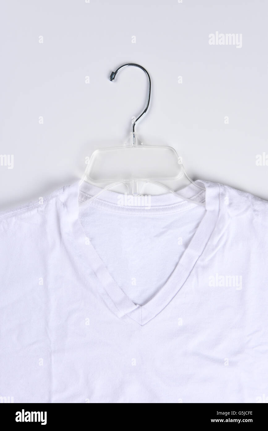 Nahaufnahme von einem weißen t-Shirt auf einem durchsichtigen Kunststoff Kleiderbügel. Hochformat. Stockfoto