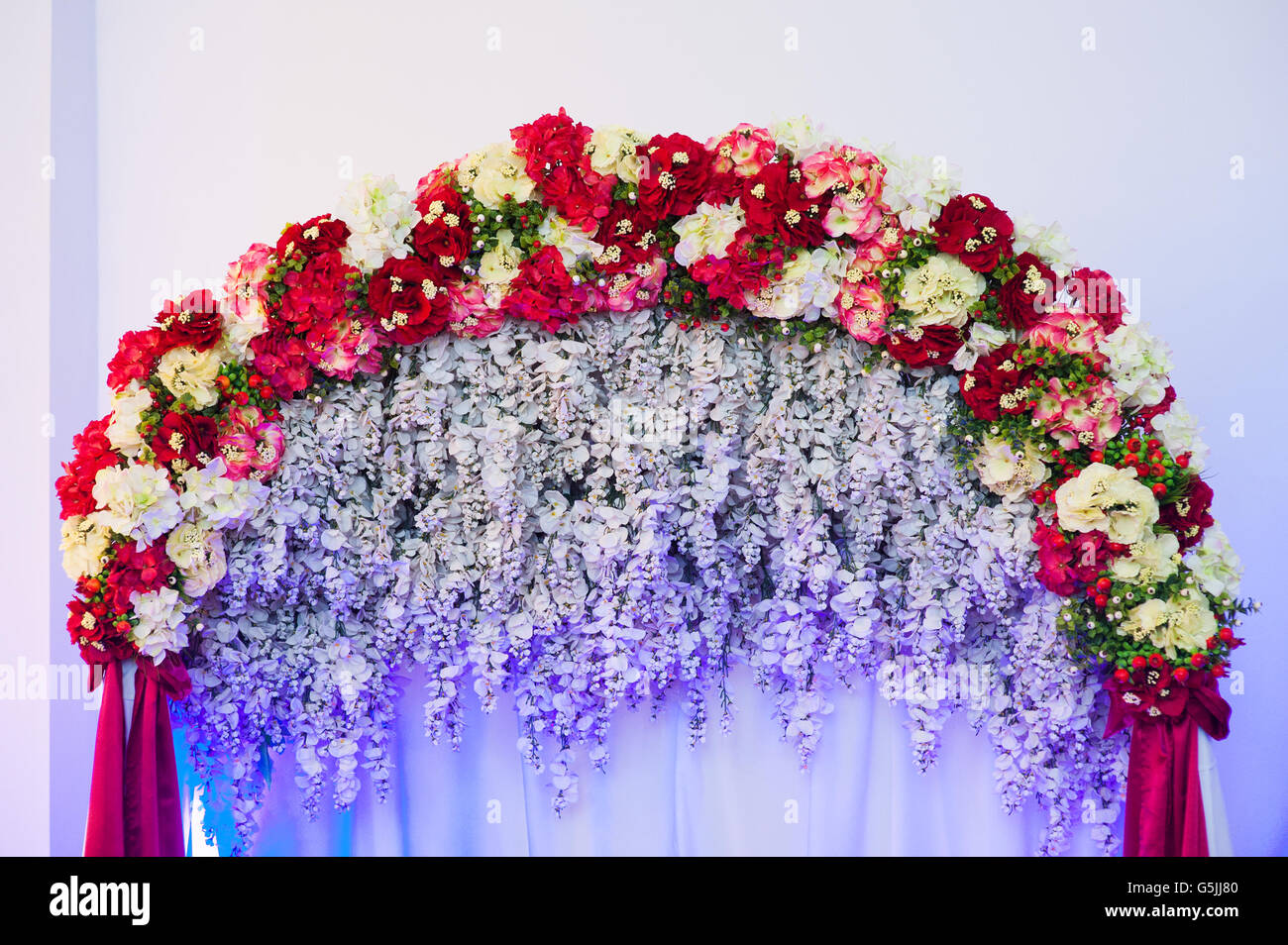 Schöne Hochzeit Bogen dekoriert mit rosa und rote Blüten im Innenbereich Stockfoto