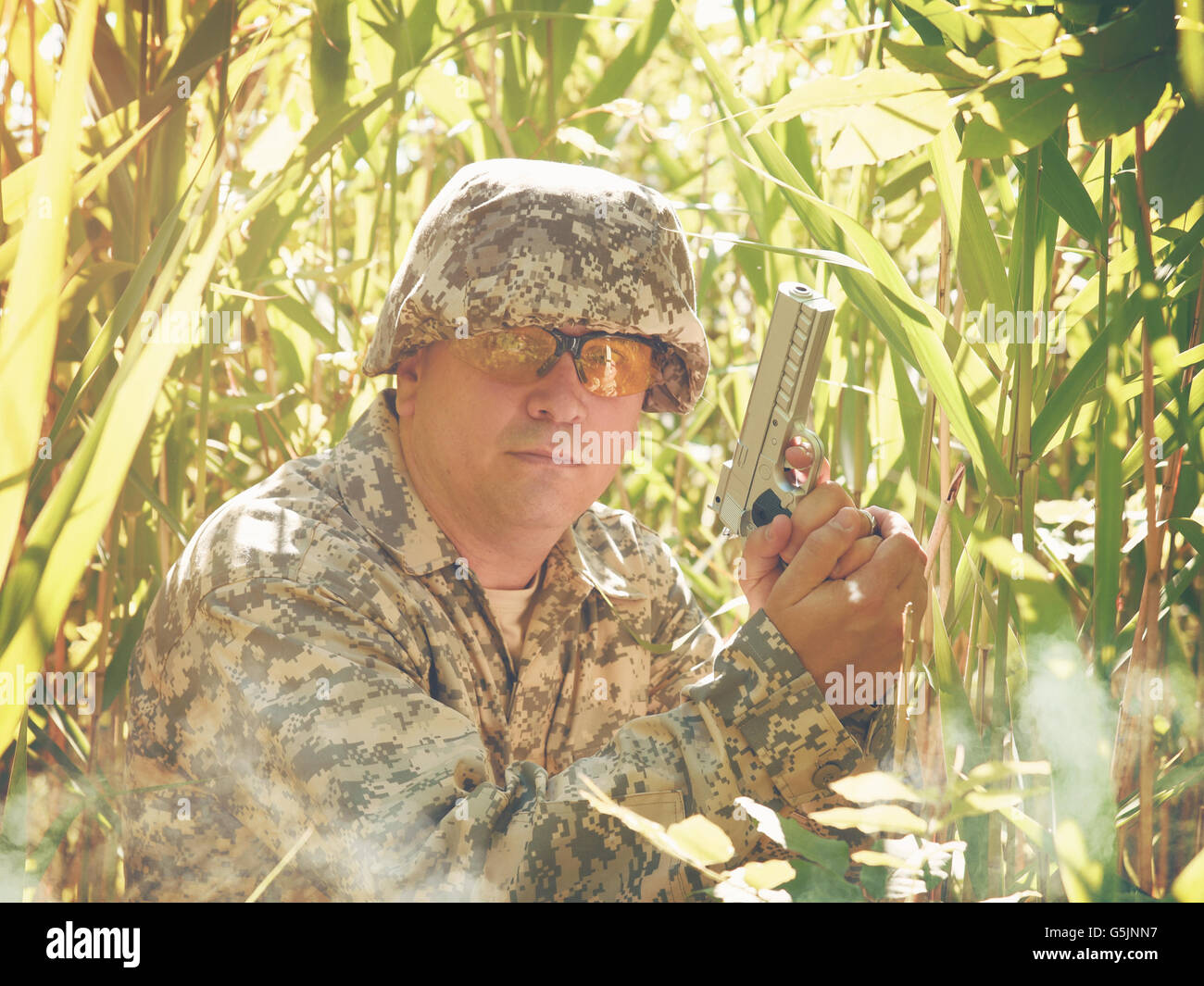 Ein Armee Soldat Mann hält eine Handfeuerwaffe in den Wald mit hohen Rasen außerhalb für Verteidigung, Sicherheit oder gegen Krieg-Konzept. Stockfoto