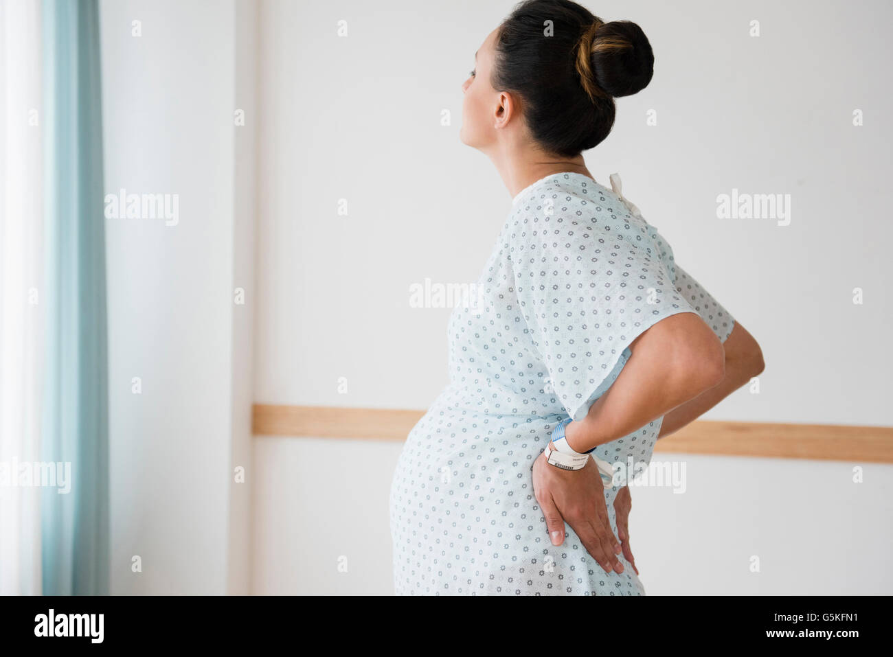 Schwanger kaukasischen mit Rückenschmerzen in Krankenhemd Stockfoto