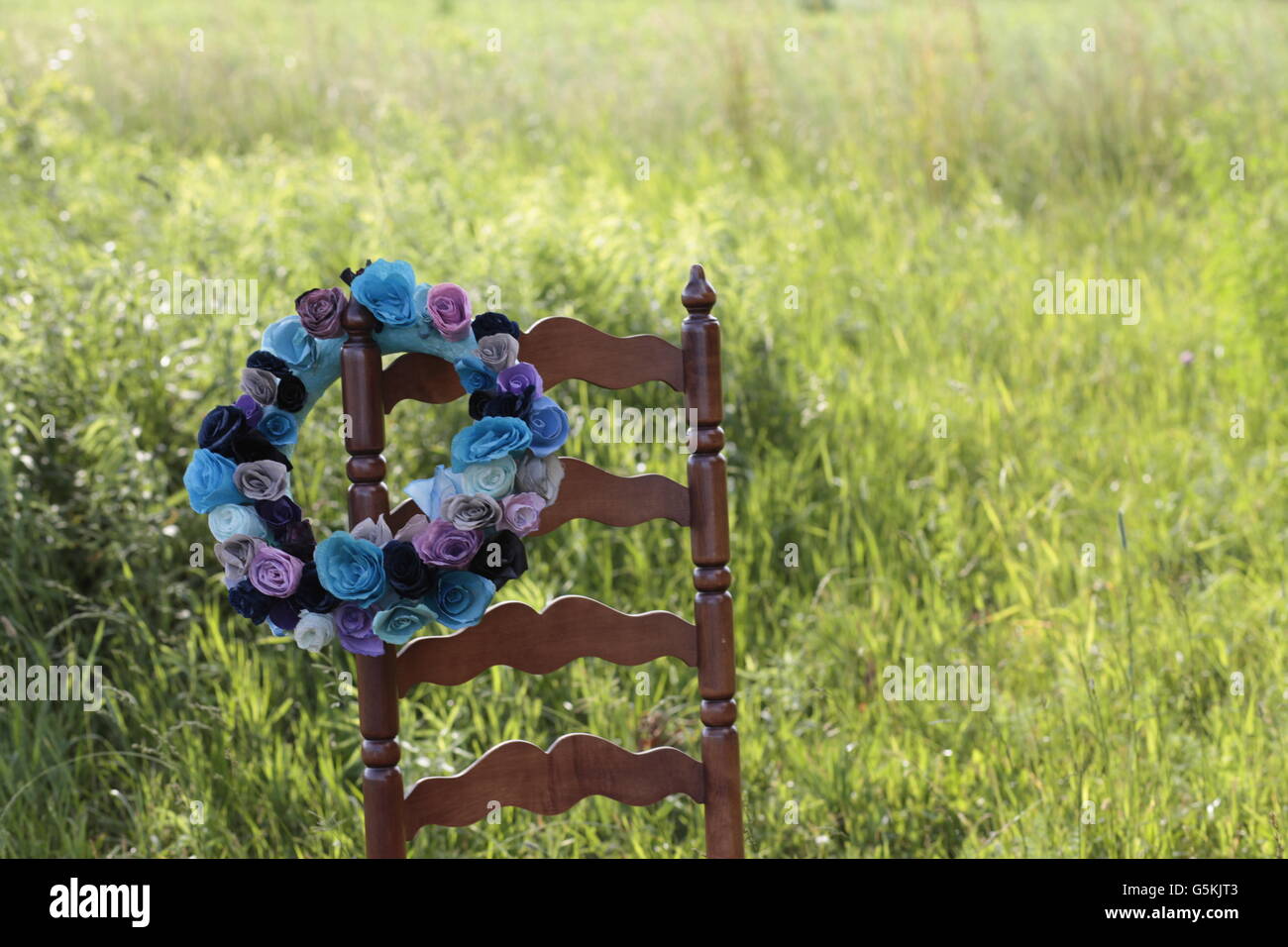 schöne blaue Blume Kranz im grünen Feld auf Leiter zurück Stuhl Stockfoto