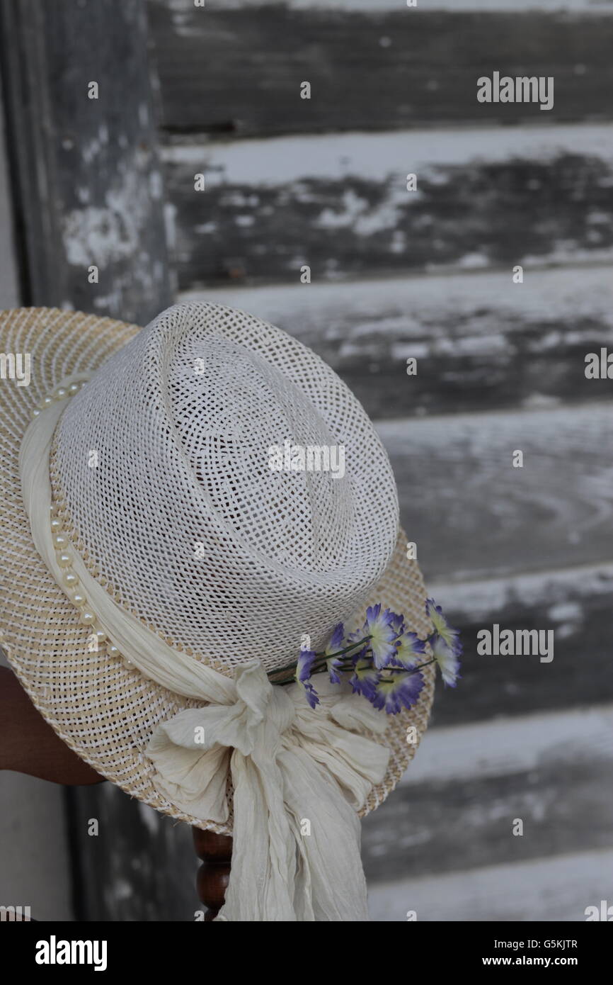 Womans Antik weißen Hut mit lila Blüten hängen gegen verwitterte graue Scheune Bauholz Abstellgleis Stockfoto