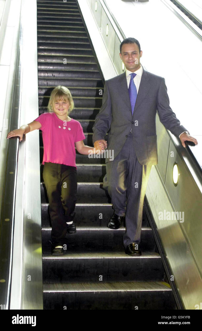 Michael Biggs, der Sohn des großen Eisenbahnräubers Ronnie Biggs, geht Hand in Hand eine Rolltreppe mit Emma Buggins im Alter von 7 Jahren aus Highams Park, East London, hinunter, um die Stroke Awareness Week zu fördern. *das Paar war an der Canary Wharf U-Bahnstation, um die Leute zu ermutigen, mehr Bewegung zu machen und die Drohung eines Schlaganfalls zu schlagen. Beide wurden von Schlaganfällen betroffen, wobei Michaels berühmter Vater darunter gelitten hatte, und Emma selbst, als sie gerade 4 Jahre alt war, einen davon litt. Stockfoto