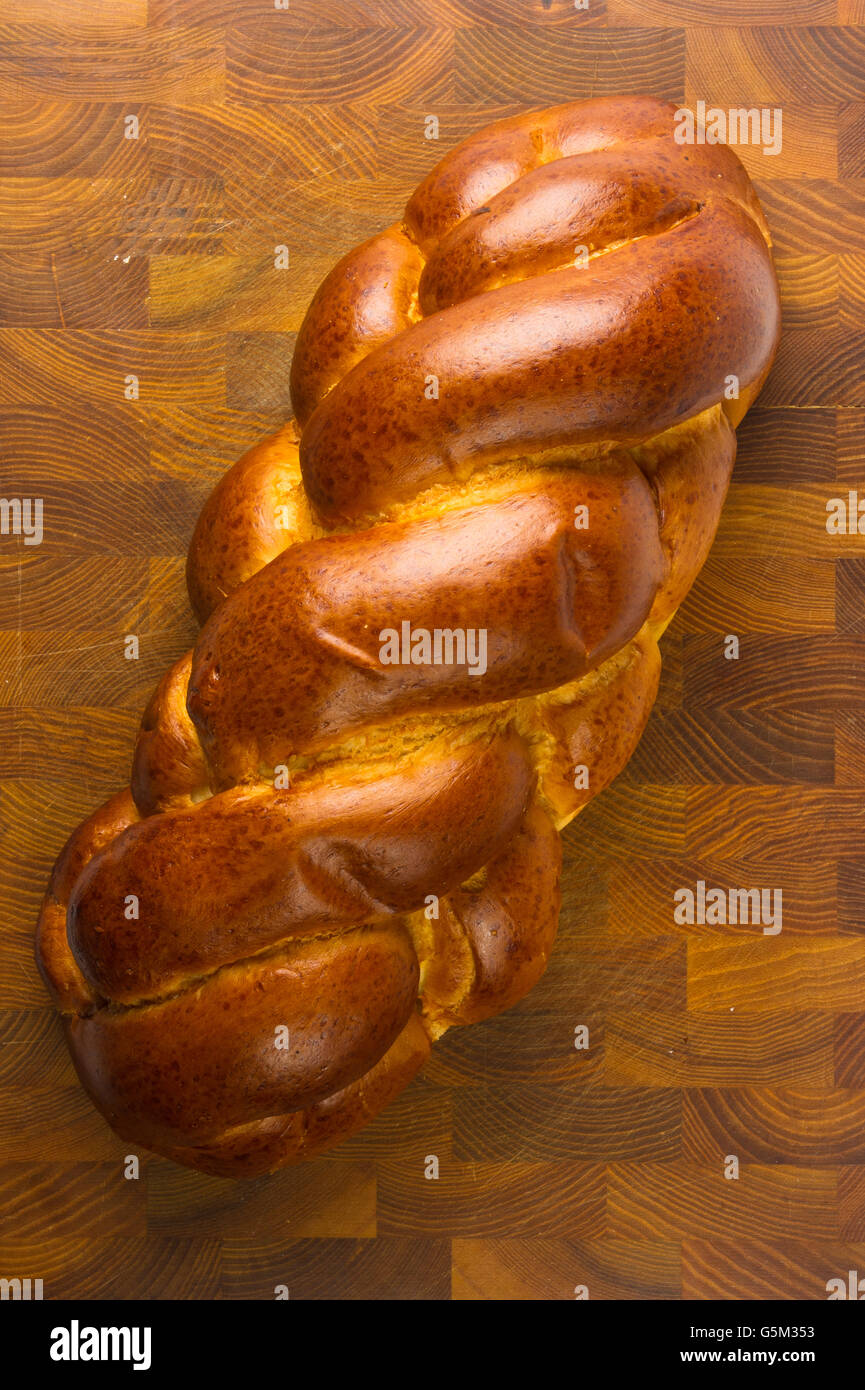 Brocken großes geflochtenes Brot auf hölzernen Hintergrund Stockfoto