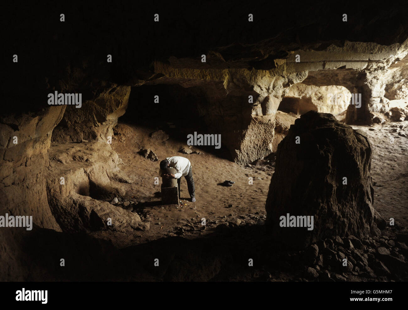 Ein Mann umarmt eine steinerne Darstellung der Hindu-Gottheit Shiva in einer Höhle der Elephanta Höhlen auf Elephanta Insel vor der Küste von Mumbai, Indien. Stockfoto