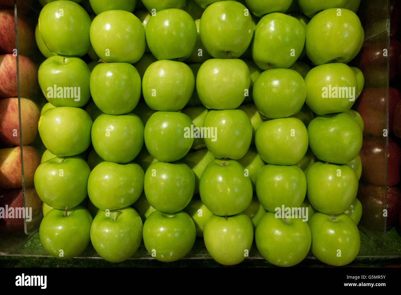 gesunde frische grüner Apfel ordnen Sie ordentlich im Stall zwischen zwei roten Apfel-Stall im Supermarkt. Stockfoto
