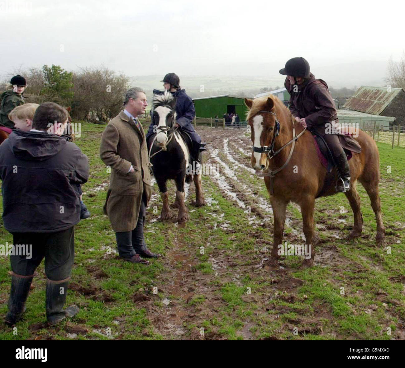 Der Prinz von Wales spricht mit Reitern während eines Vsit zum Cantref Riding Center, in den Brecon Beacons, Mitte Wales. In seinen Brogen trotzte er schlammigen Feldern und wurde vom Besitzer des Reitzentrums Colin Evans begleitet (links im Bild, mit seinem Sohn Rhys, 3 Jahre alt). * ... Das Reitzentrum waas wurde von der Maul- und Klauenseuche schwer getroffen, als während der Krise mehr als 30,000 Schafe der Brecon Beacons geschlachtet wurden und mehr als 50 % der vom Reitzentrum genutzten Trekkingrouten geschlossen blieben. Stockfoto