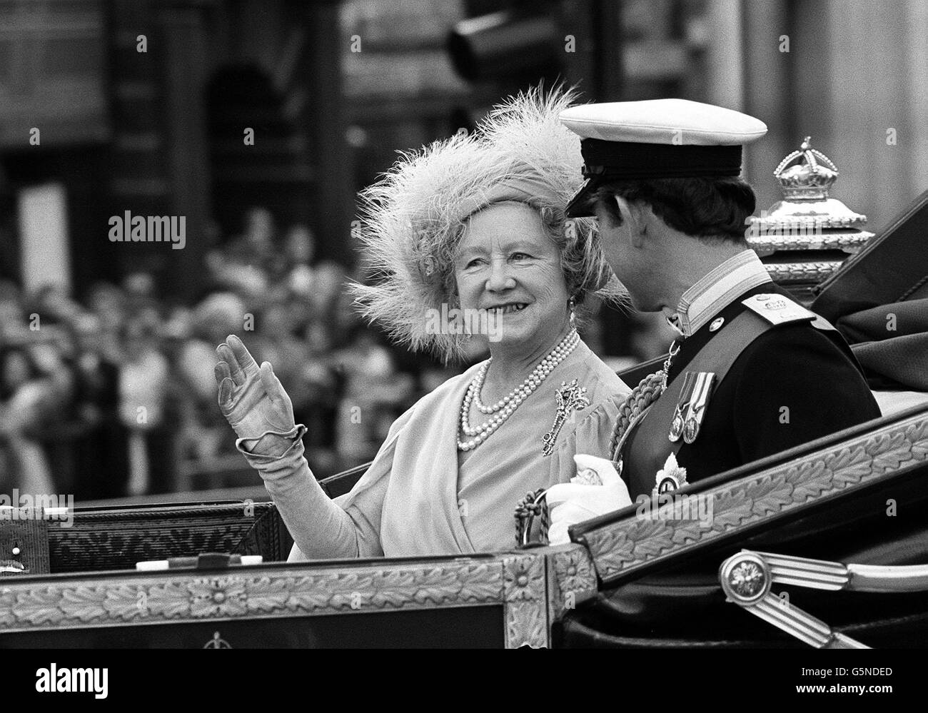Die Königin Mutter gibt eine Welle, wenn sie den Buckingham Palace in einer 1902 State Road Landau auf dem Weg zur St Paul's Cathedral für ihren 80. Geburtstag Dankgottesdienst verlässt, begleitet von Prinz Charles. Stockfoto