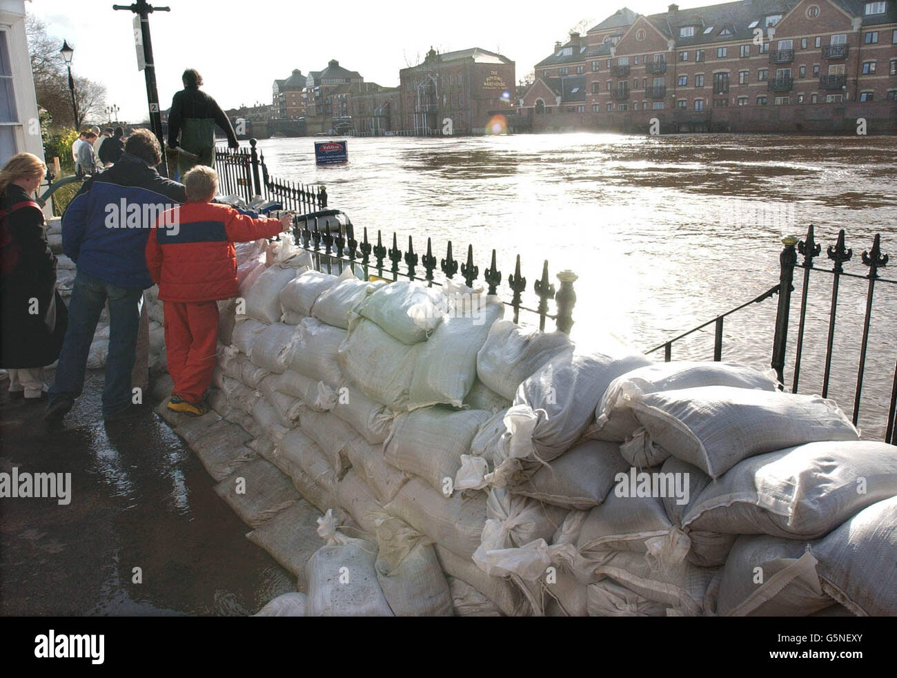 Bewohner von York in einer vertrauten Position, während sie die River Ouse aufsteigen im Stadtzentrum von hinter Sandsackwänden beobachten, die eilig gebaut wurden, um zu verhindern, dass Hochwasser in ihre Häuser am Flussufer fließt. Stockfoto