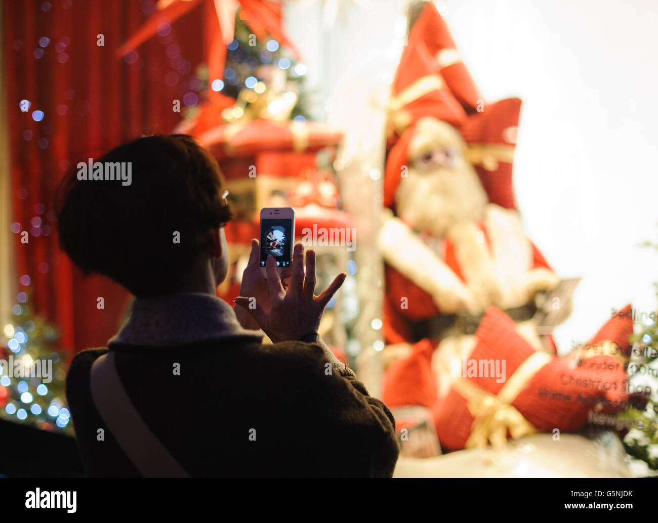 Weihnachtseinkäufe. Ein Shopper macht ein Foto von einer Schaufensteranlage in einem Weihnachtsgeschäft in der Oxford Street im Zentrum von London. Stockfoto
