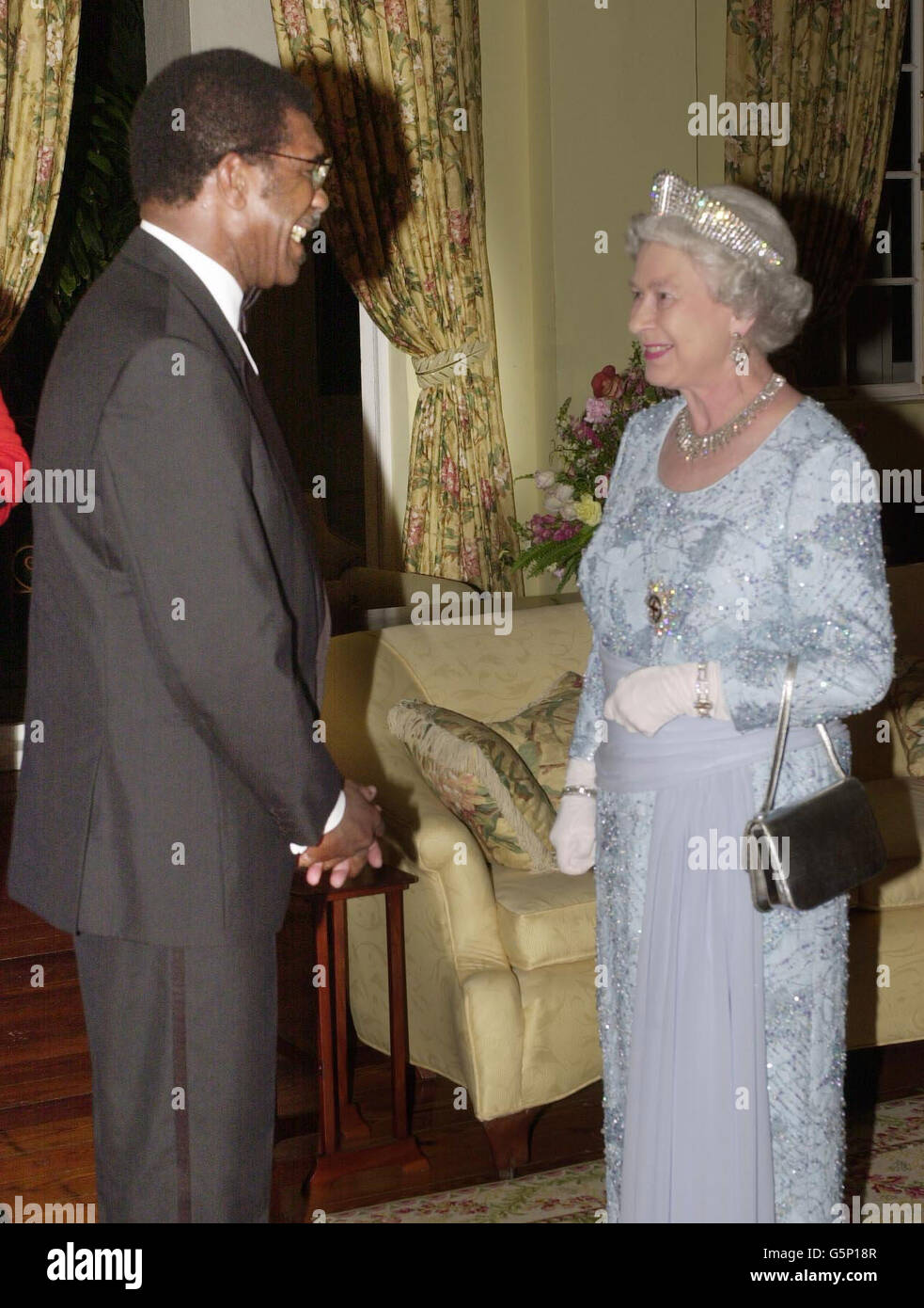 Königin Elizabeth II. Spricht mit dem britischen Gewerkschaftsführer Bill Morris vor einem Bankett, das sie in Kingston mit dem Generalgouverneur Sir Howard Cooke, ihrem Vertreter in Jamaika, für den Premierminister Percival Patterson und andere Würdenträger der Insel veranstaltet hat. * Sie war gezwungen, bei Kerzenlicht zu speisen, nachdem ein Stromausbruch die Residenz in Dunkelheit gestürzt hatte. Früher, bewacht von Scharfschützen und Geheimdienern, trotzte sie dem von Verbrechen heimgesuchten, in der Innenstadt gelegenen Kingston, wo Yardie-Drogenbanden herrschen. Am Mittwoch fliegt sie nach Montego Bay. Stockfoto