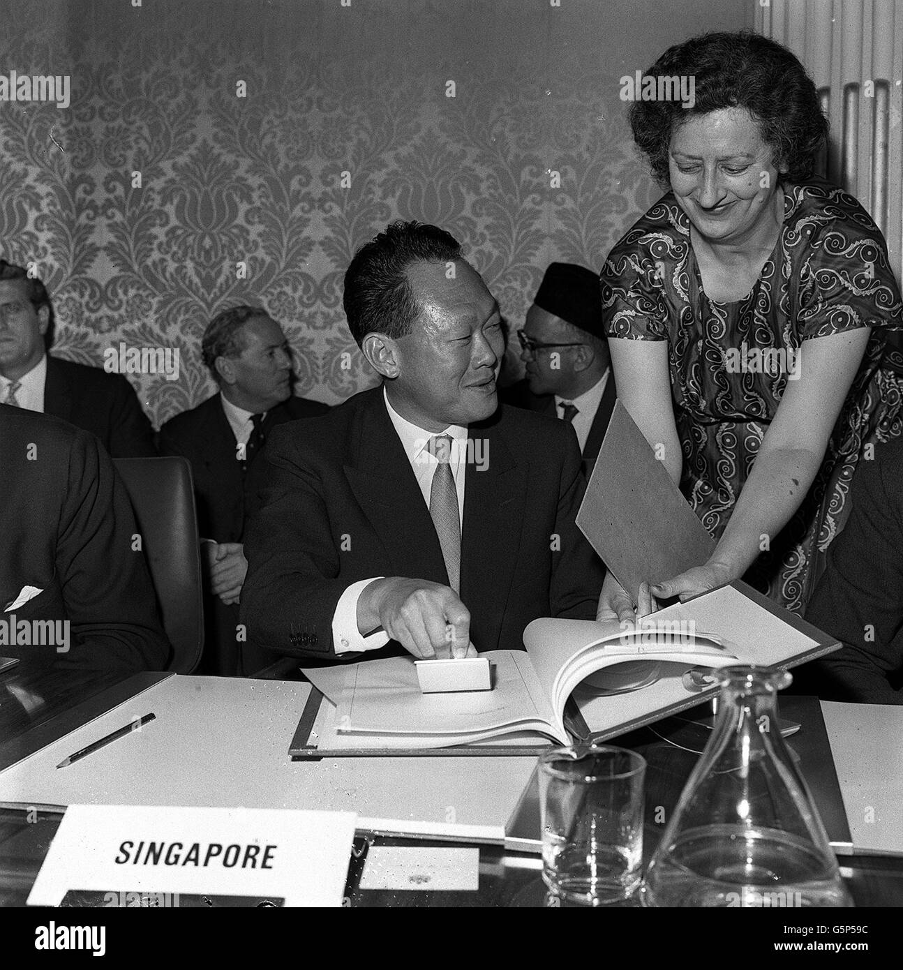 Herr Lee Kuan Yew wendet lächelnd einen Fleck an, nachdem er als einer der Delegierten Singapurs das Abkommen zur Gründung der Föderation von Malaysia unterzeichnet hat. Stockfoto
