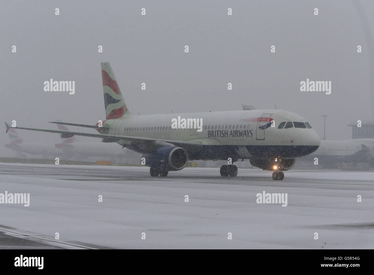 Ein Flugzeug sitzt auf der Start- und Landebahn am Flughafen Heathrow, als Schnee Straßen schloss und der Zug heute durch Großbritannien fuhr, wobei die wichtigsten Pendlergürtelgebiete Südenglands den schlimmsten Gefahren am Morgen entkommen sind. Stockfoto