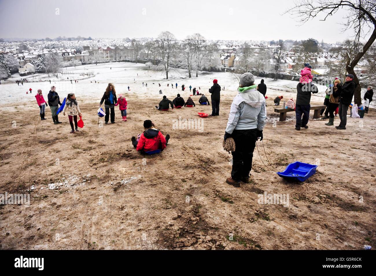 Schlittenfahrer haben immer noch Spaß, da der Schnee langsam dem Schlamm auf dem Gipfel des Hügels im Arnos Park in Brislington, Bristol, weicht, wo Schnee vor dem Wochenende gefallen ist und die eisigen Temperaturen den Schnee bewahrt haben. Stockfoto