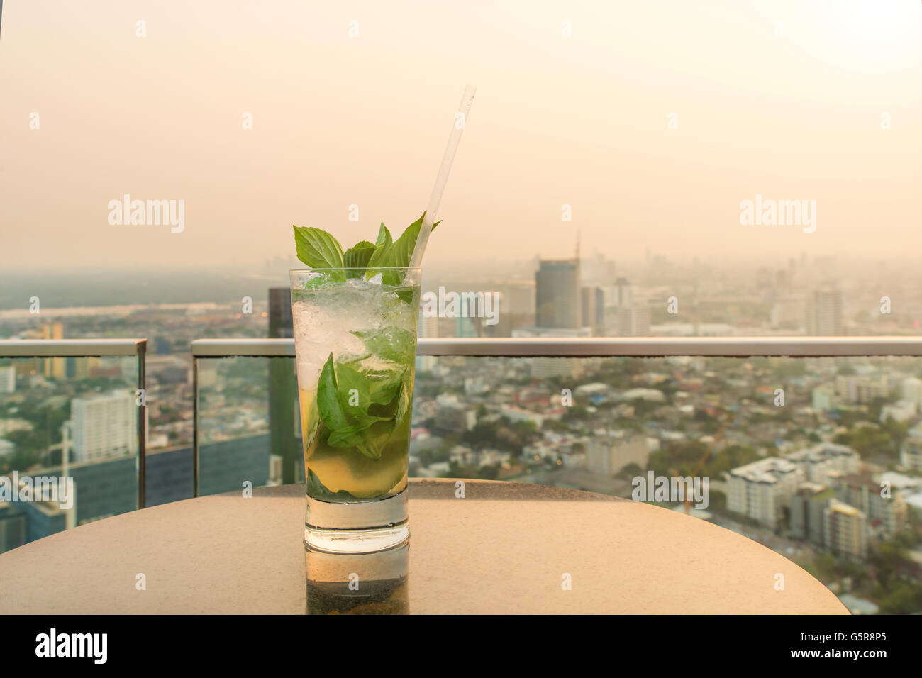 Mojito cocktail am Tisch in der Bar auf der Dachterrasse. Bar auf der Dachterrasse in Bangkok, Thailand. Bar auf der Dachterrasse bei Sonnenuntergang. Stockfoto