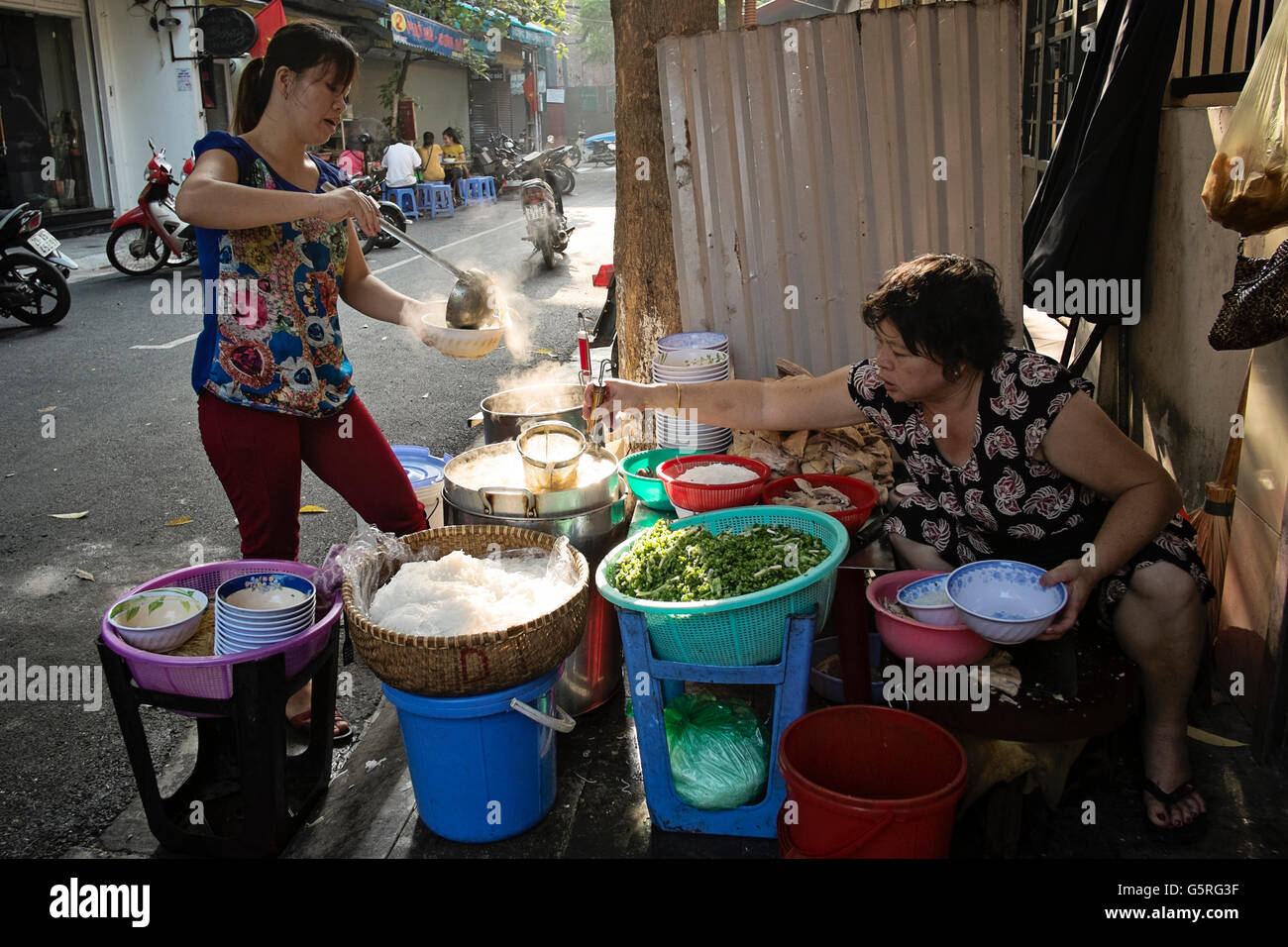 Zwei Frauen mittleren Alters dienen Reis, Nudeln und Gemüse an einem Straßenstand im alten Viertel von Hanoi, Hoan Kiem, Vietnam Stockfoto