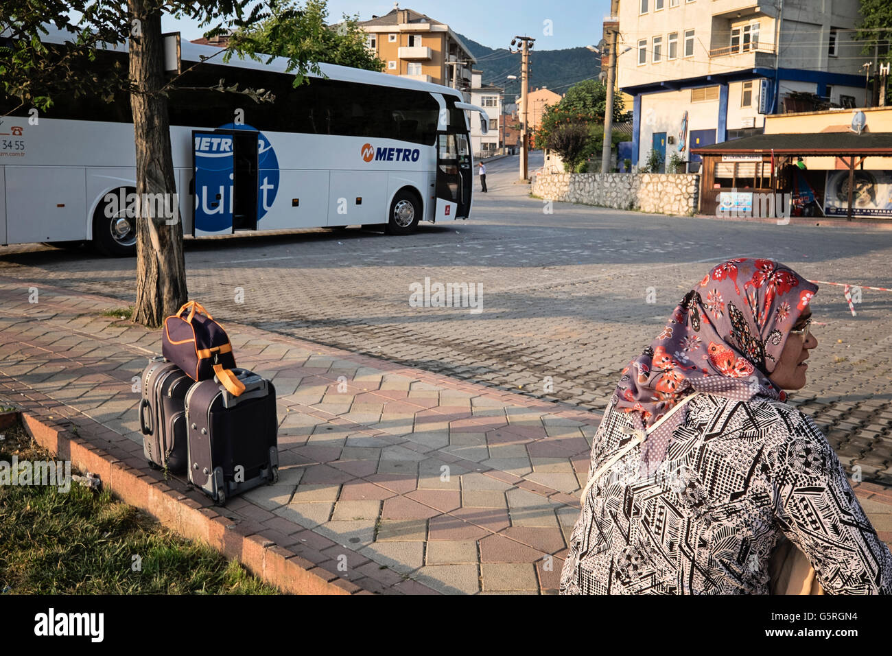 HorizontalA Frau wartet mit Ihr Gepäck an einem Busbahnhof in Amasra, Bartin, Türkei Stockfoto