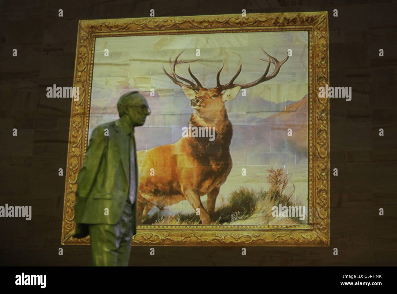 Eine Projektion des Monarch of the Glen, 1851, von Edwin Henry Landseer, vor einer Statue von Donald Dewar, wie sie auf der Glasgow Royal Concert Hall projiziert wird, um ein Online-Archiv von Kunst zu publizieren Stockfoto